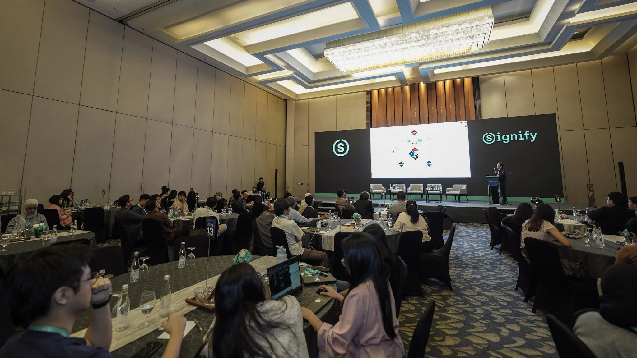 Wide view of Herwin Suryadi Gunawan presenting at Signify Innovation Day to an audience in a hotel ballroom.