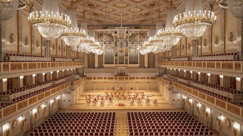Konzerthaus Berlin’s concert hall with tiered balconies, crystal chandeliers, red audience seats, and a stage beneath a large pipe organ.
