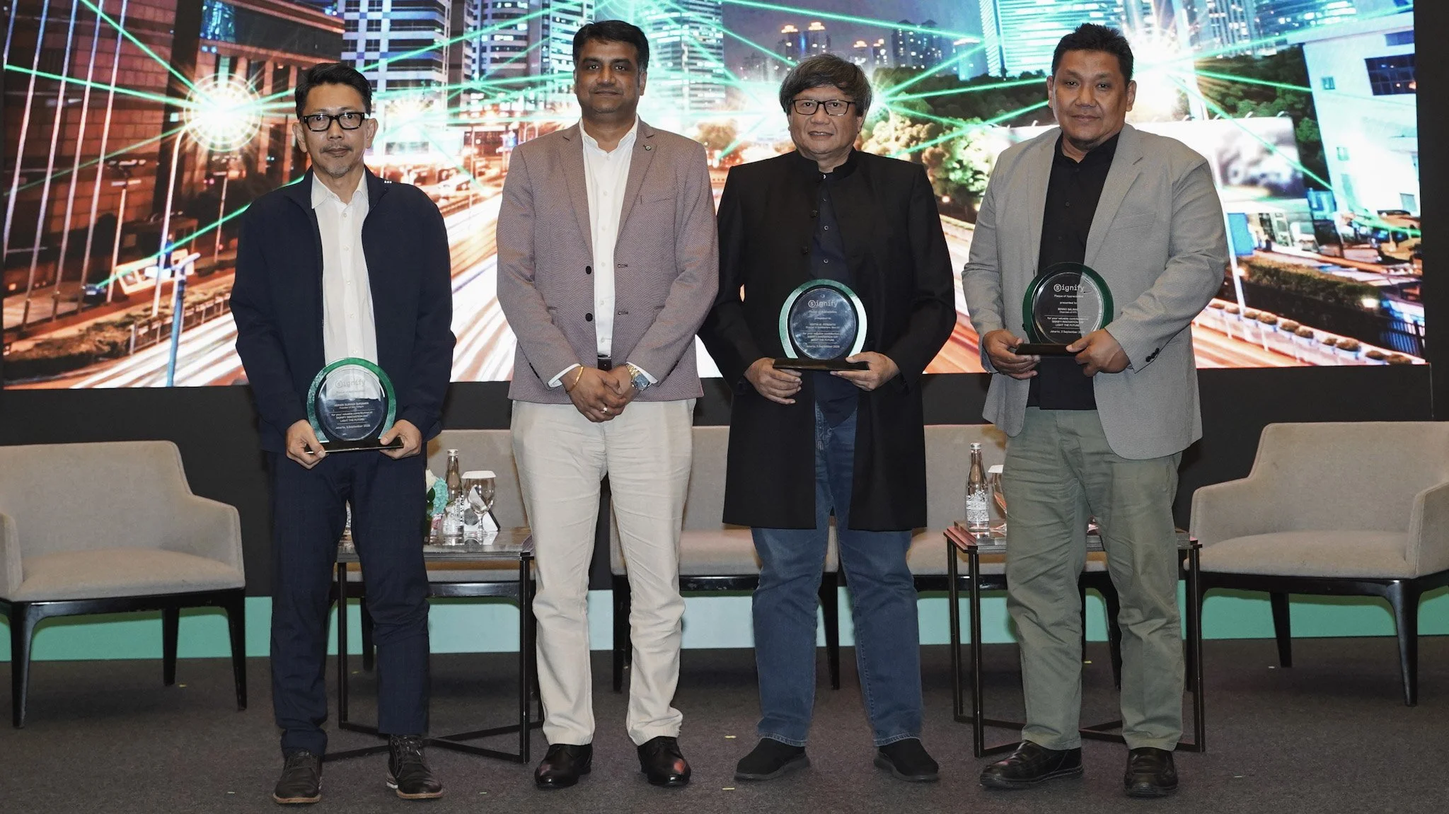 Speakers and Signify Indonesia representatives standing on stage with recognition plaques at Signify Innovation Day.