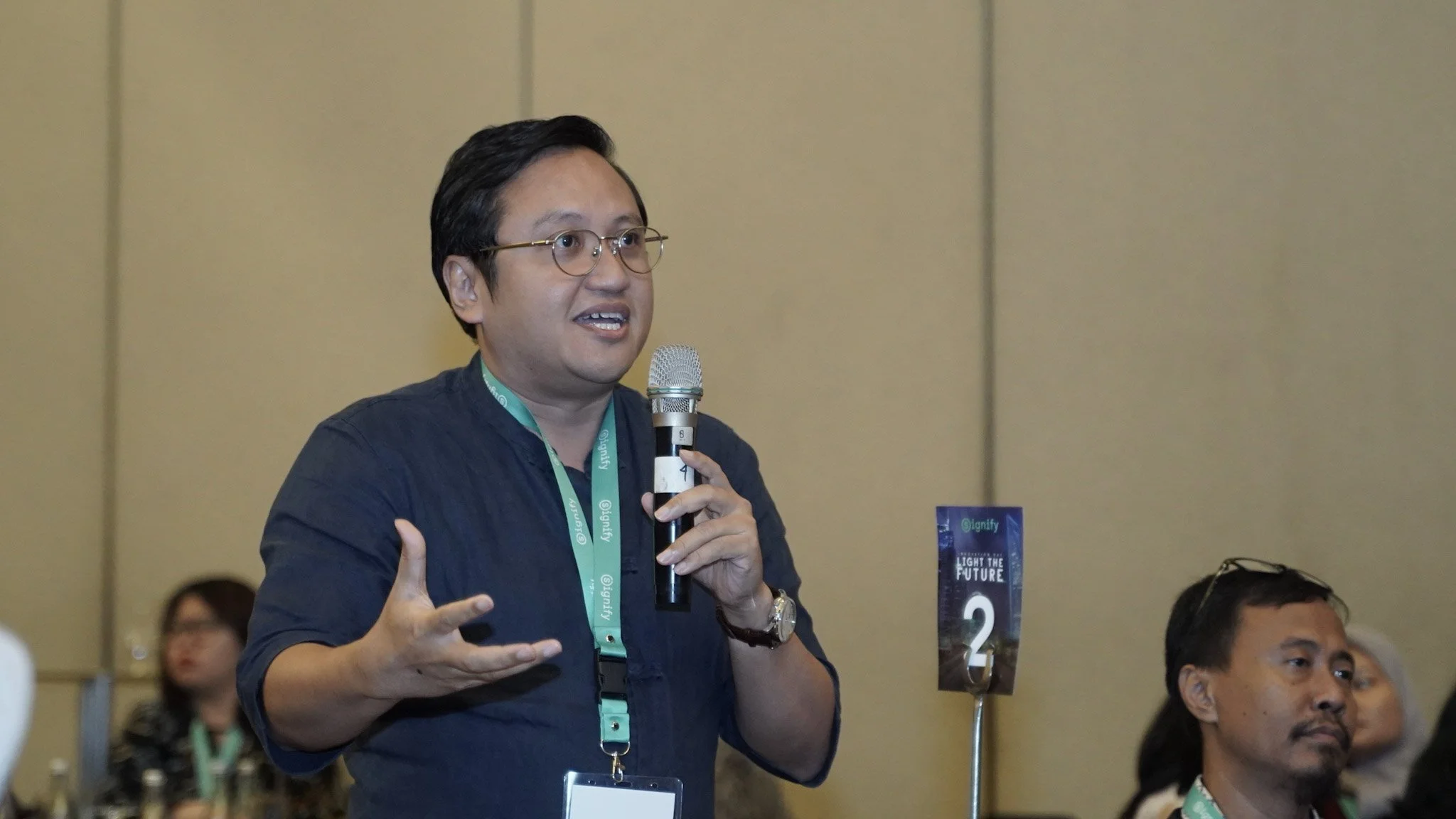 Audience member asking a question with a microphone during the Signify Innovation Day discussion session.