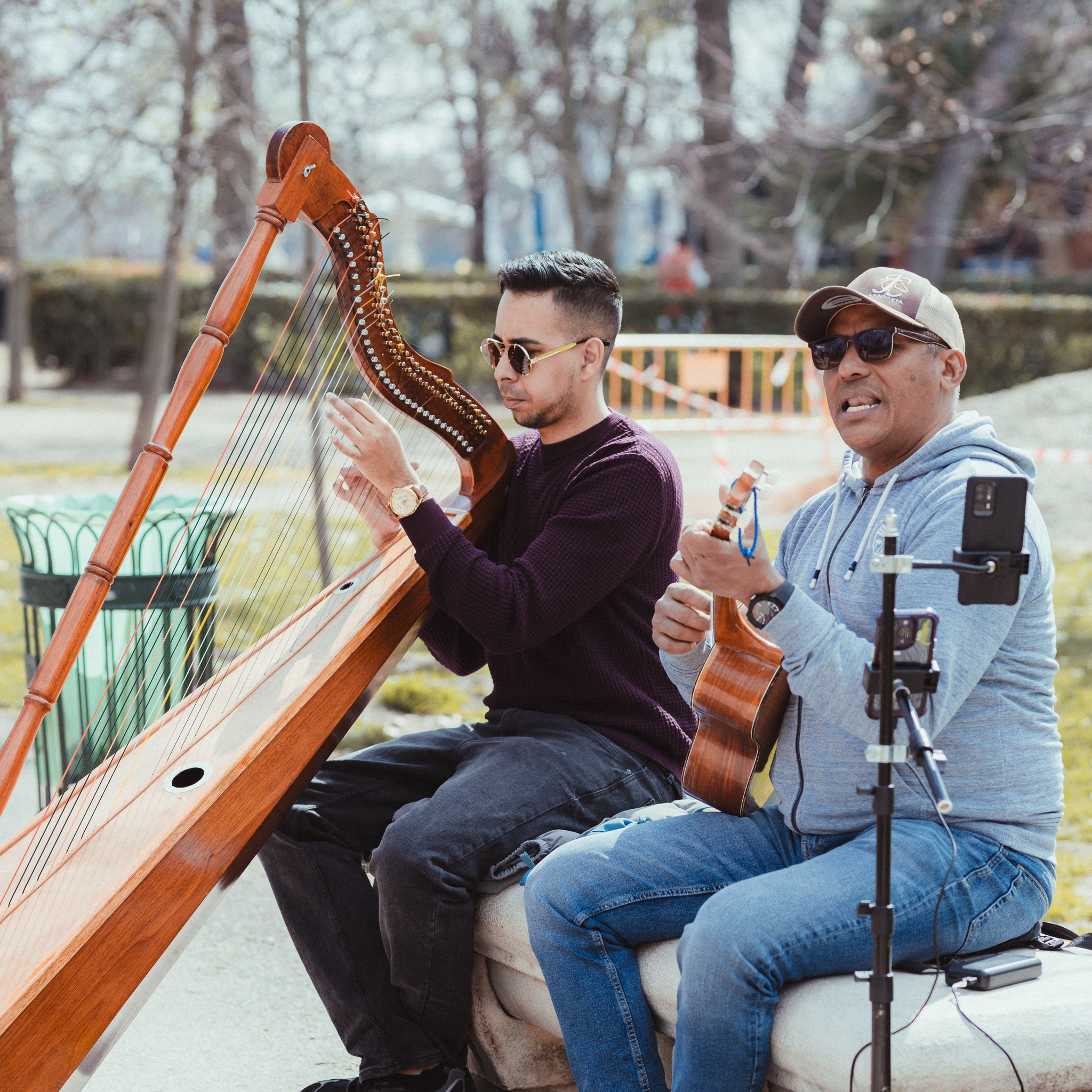 Two street musicians playing a wooden harp and a small guitar for visitors in El Retiro Park, Madrid