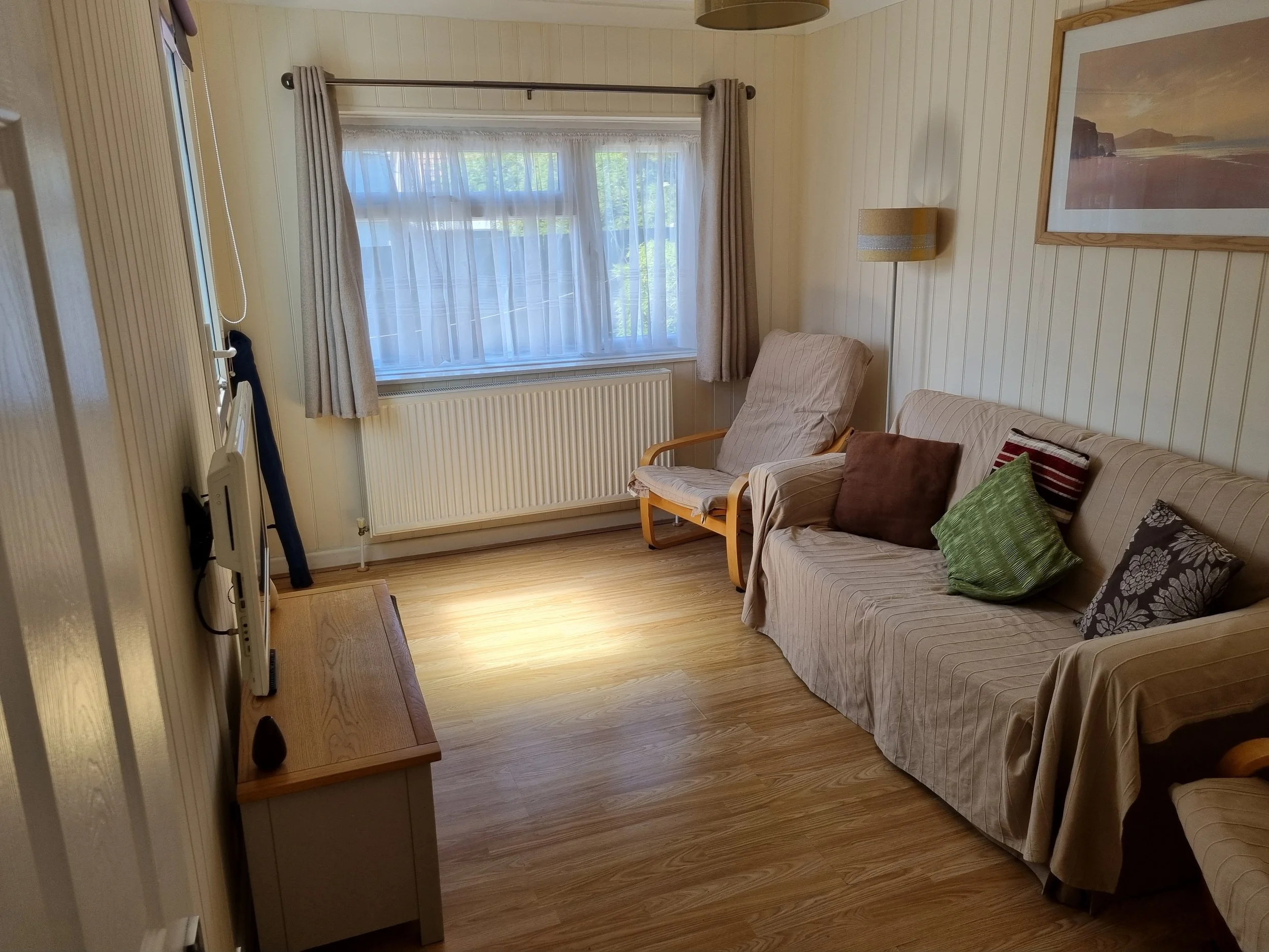 Lounge with window overlooking the garden and back door leading to the raised deck. 