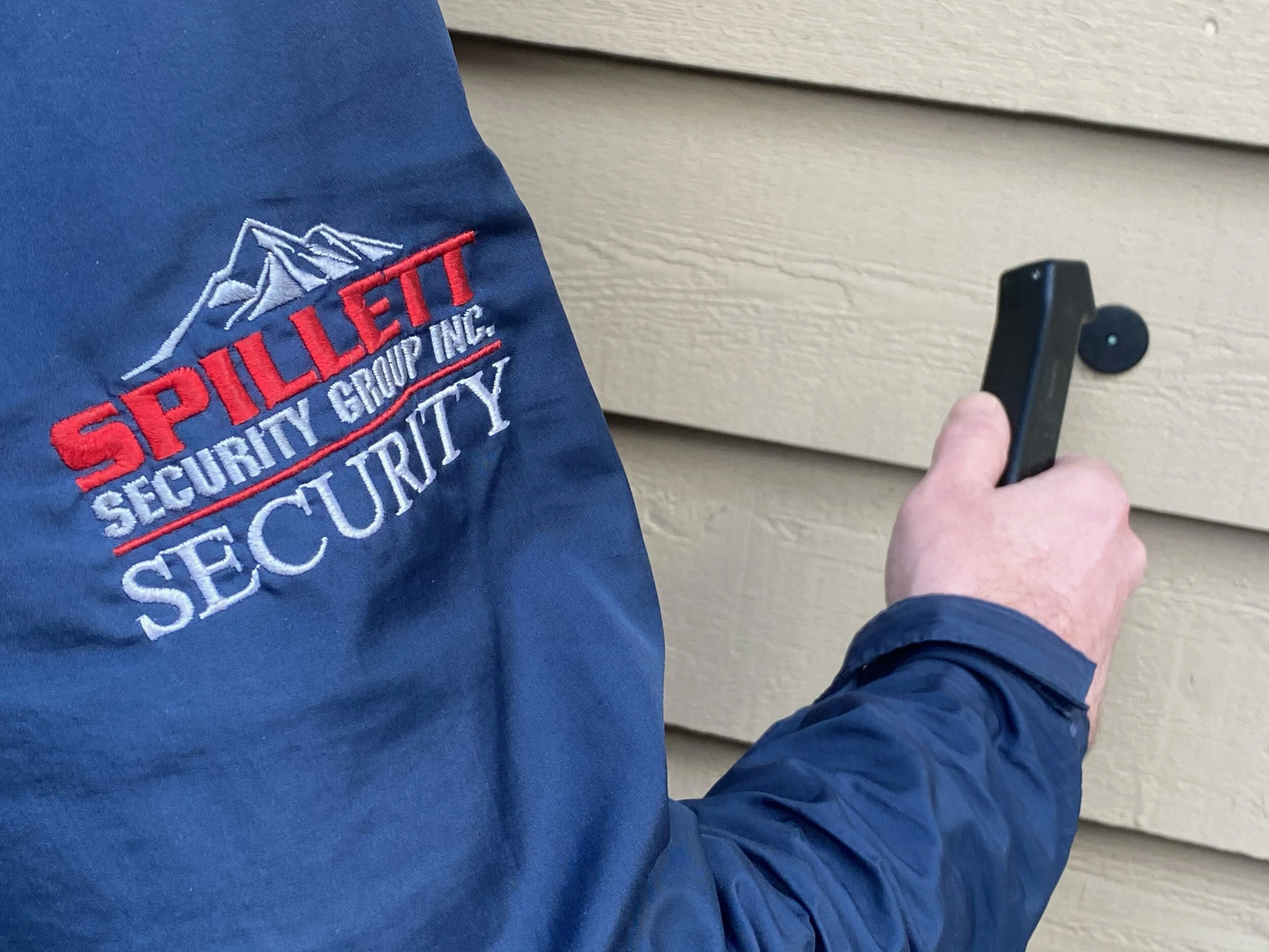 A security officer is using a metal detector on a wall.