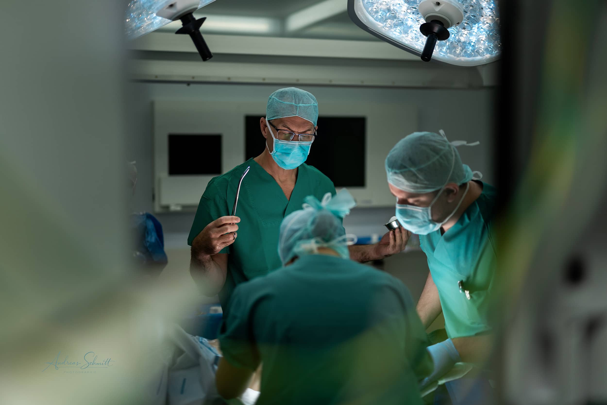 Chirurgen und medizinisches Personal während einer Operation im Operationssaal, alle tragen Schutzmasken, Kappen und medizinische Anzüge.
