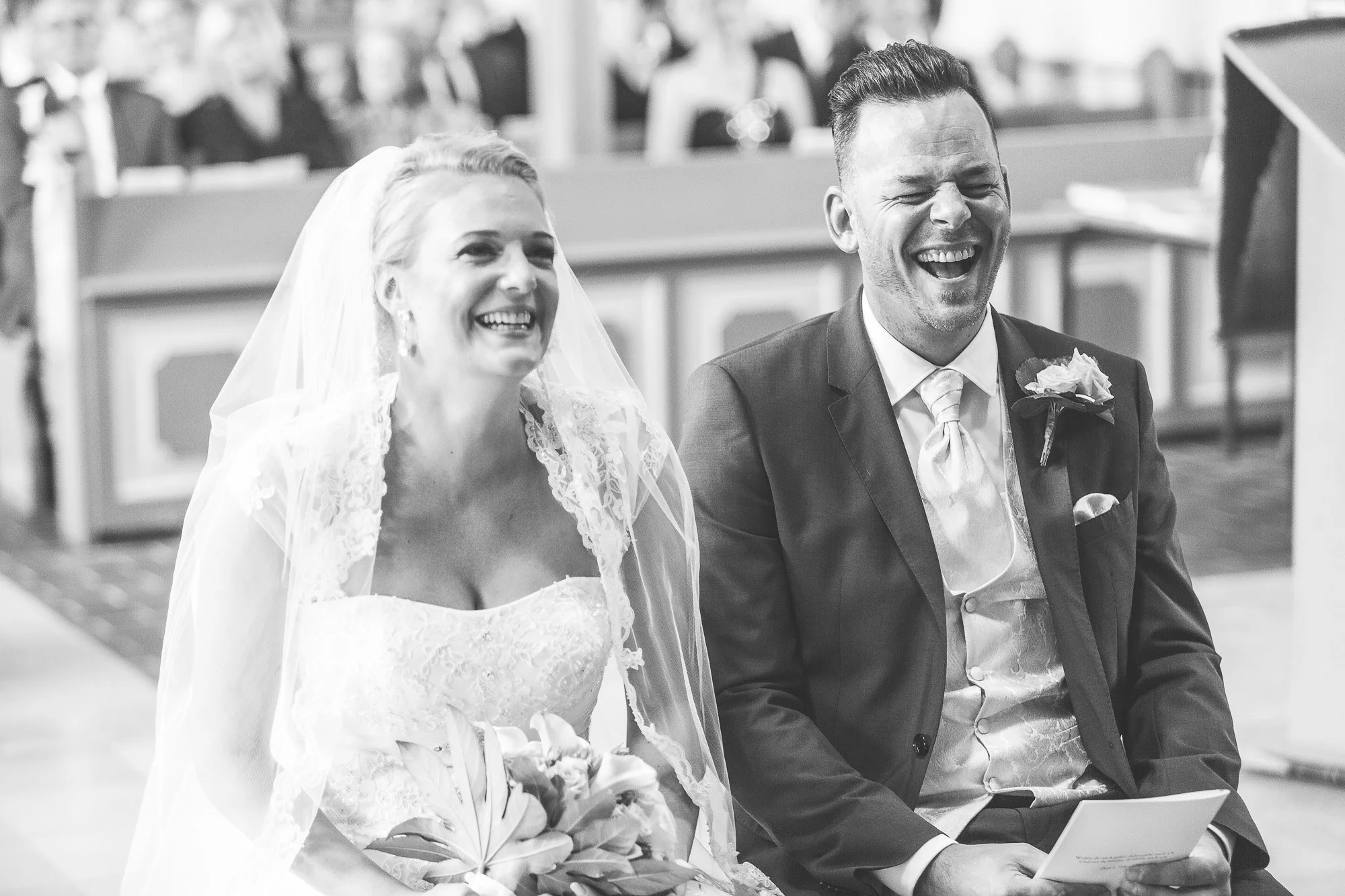 Braut und Bräutigam lachen während ihrer Hochzeitszeremonie in einer Kirche.