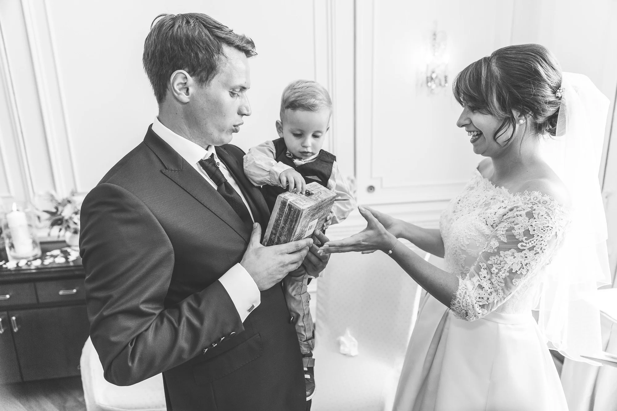 Ein Mann in einem Anzug, eine kleine Person und eine Frau in einem Hochzeitskleid, die sich gegenseitig Geschenke geben.