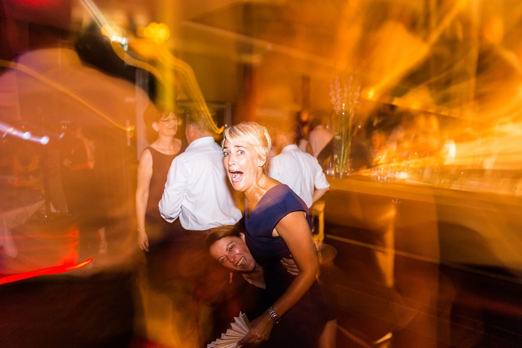 Menschen tanzen auf einer Feier mit buntem Licht und stimmungsvoller Atmosphäre.