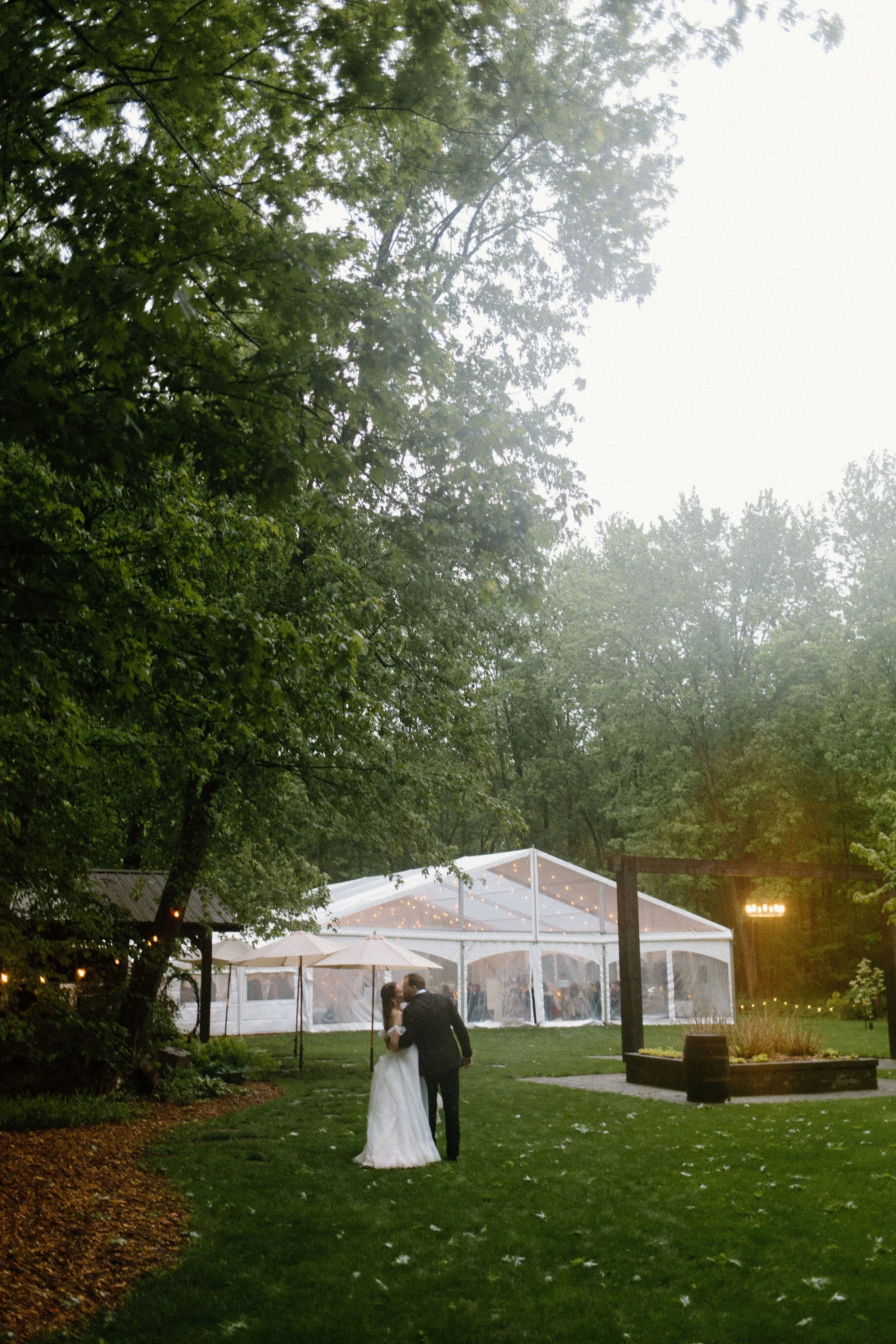  Bride and Groom splash around in the rain puddles during their wedding reception at The Clearing.  