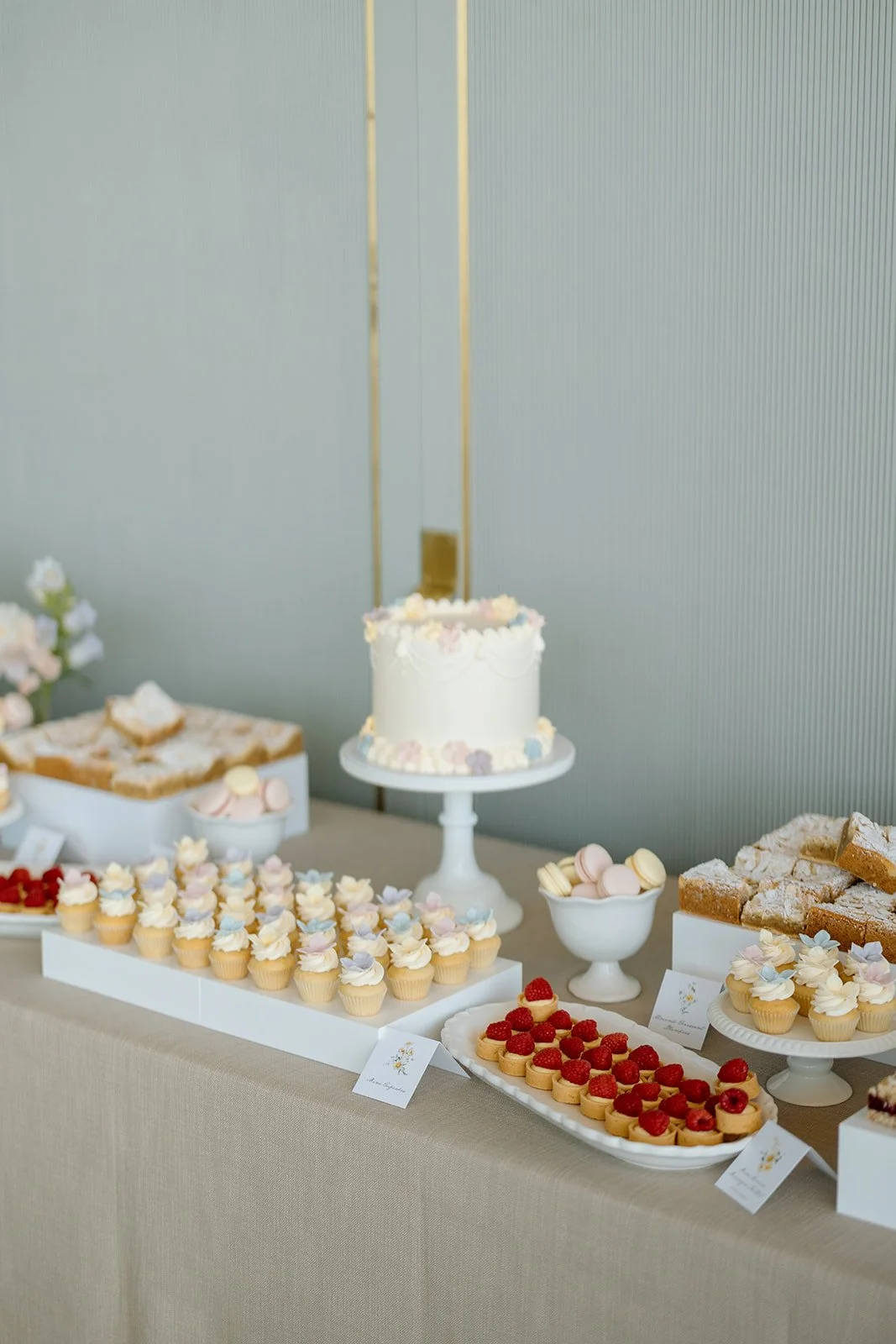  A curated dessert table featured gourmet treats, including perfectly drizzled berry crumble bars alongside classic French macarons. By The Dessert Room 
