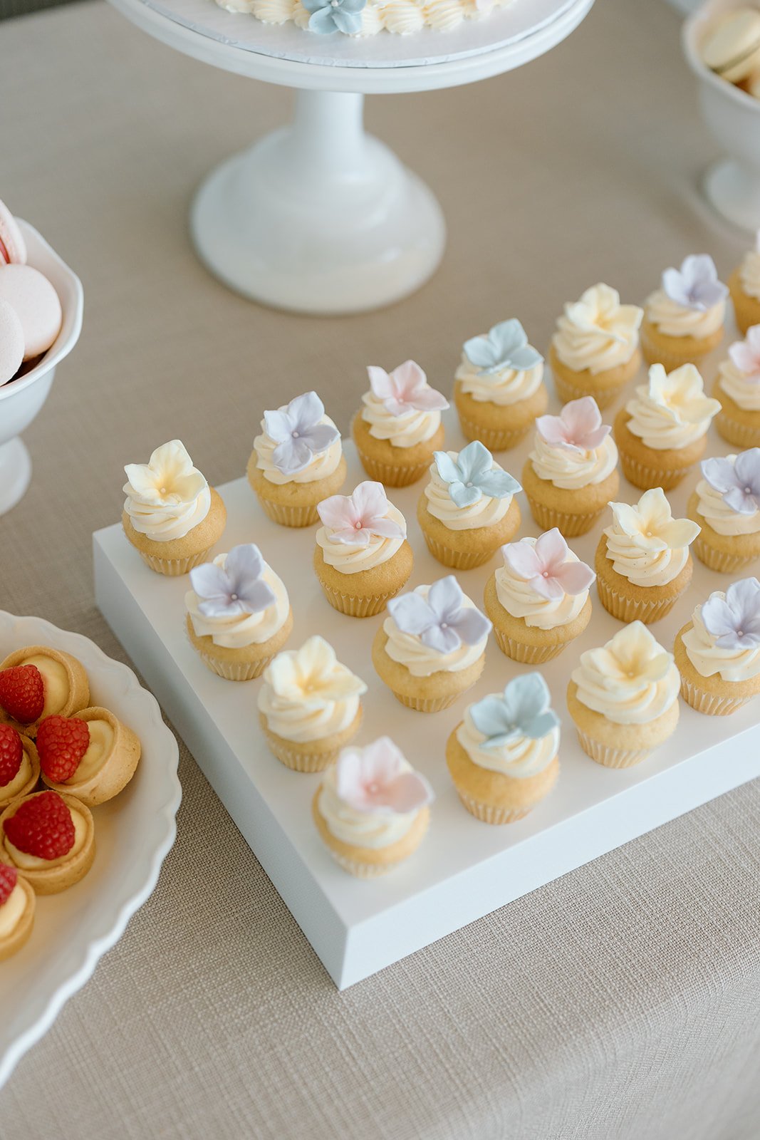  A curated dessert table featured gourmet treats, including perfectly drizzled berry crumble bars alongside classic French macarons. By The Dessert Room 