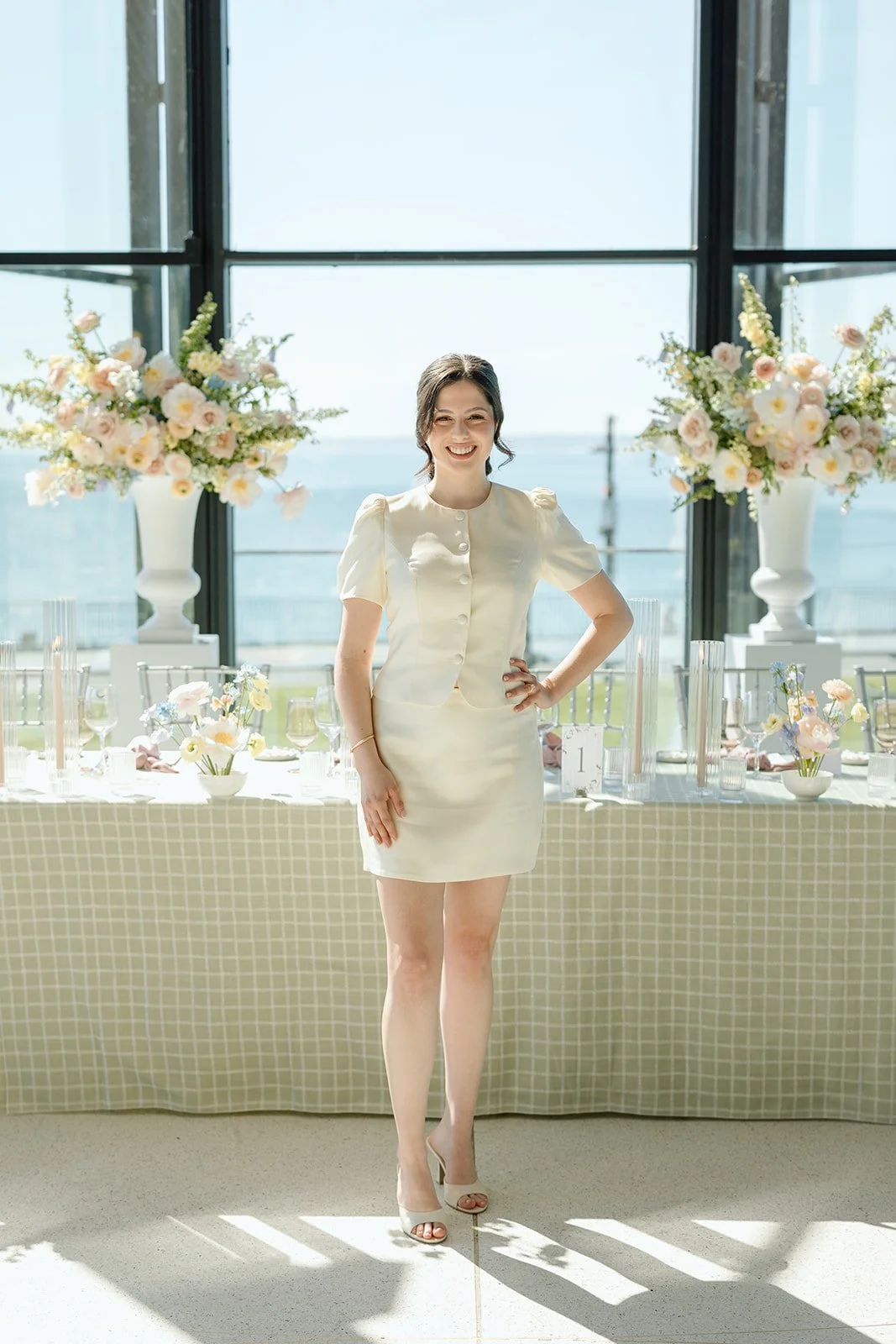  The beautiful bride-to-be standing in front of her stunning head table setup, glowing in the natural waterfront light. 