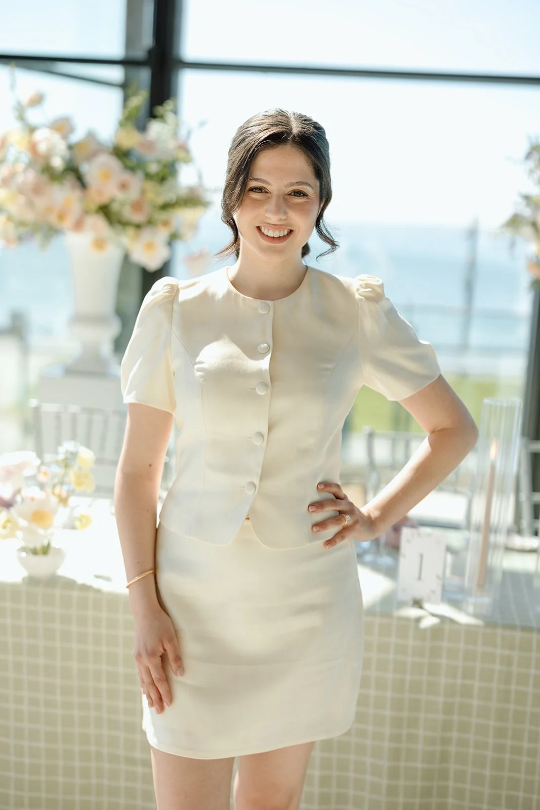  Our radiant bride-to-be, Michela, wearing a chic modern ivory skirt suit, perfectly framed by her custom head table floral backdrop. 