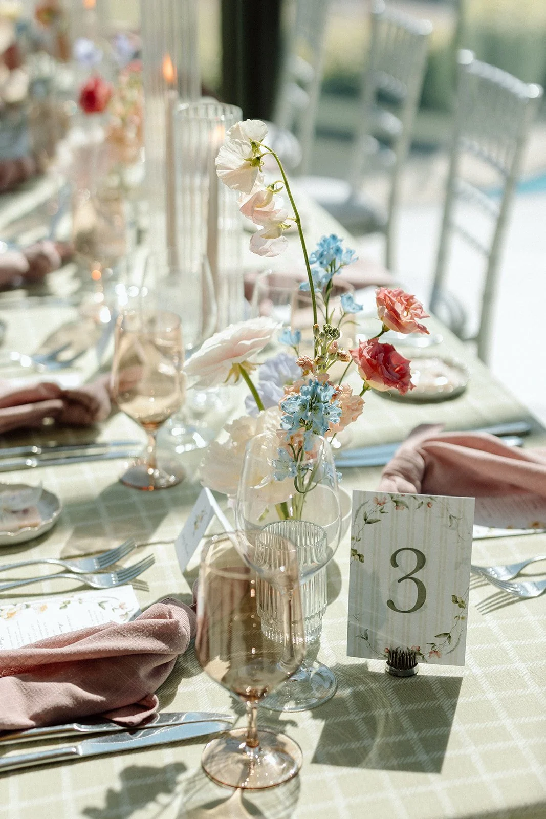  Close-up of a modern bridal shower tablescape with sage plaid linen, mauve napkins, and garden centerpieces. 
