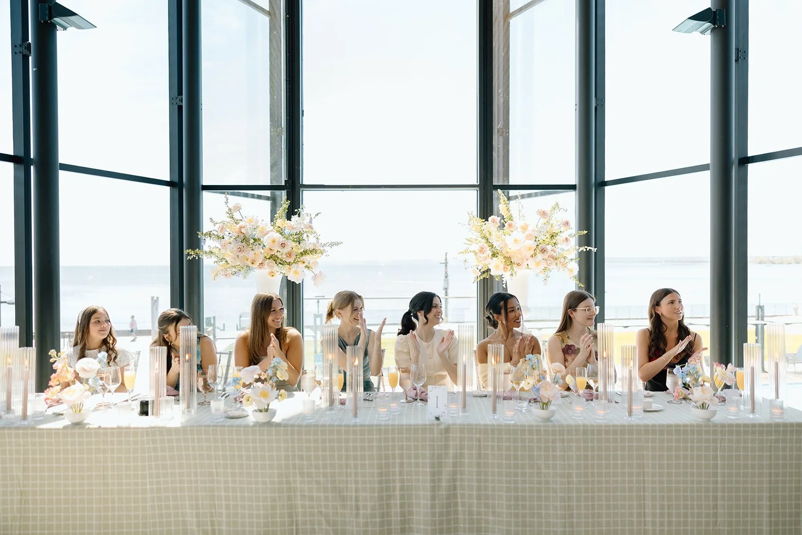  Bride sits with her bridesmaids at the head table among her guests at Spencer’s on the Waterfront. 
