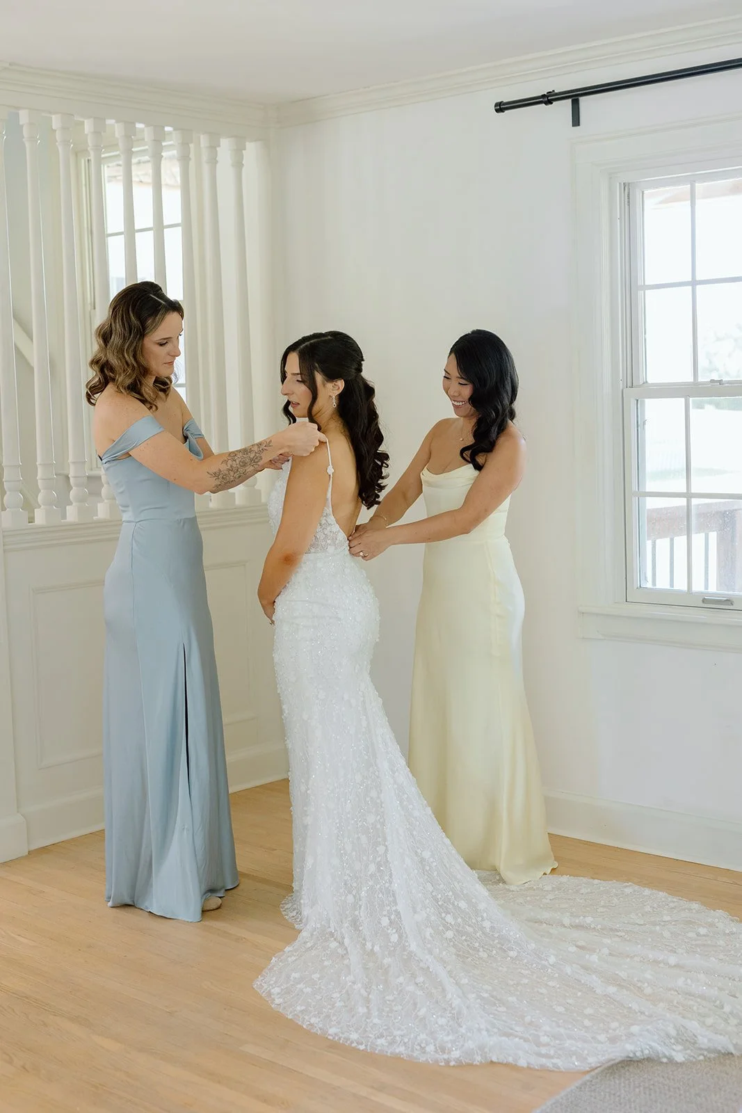  Bridesmaids help bride into her wedding gown before her First Look at Willowfarm House NOTL. 