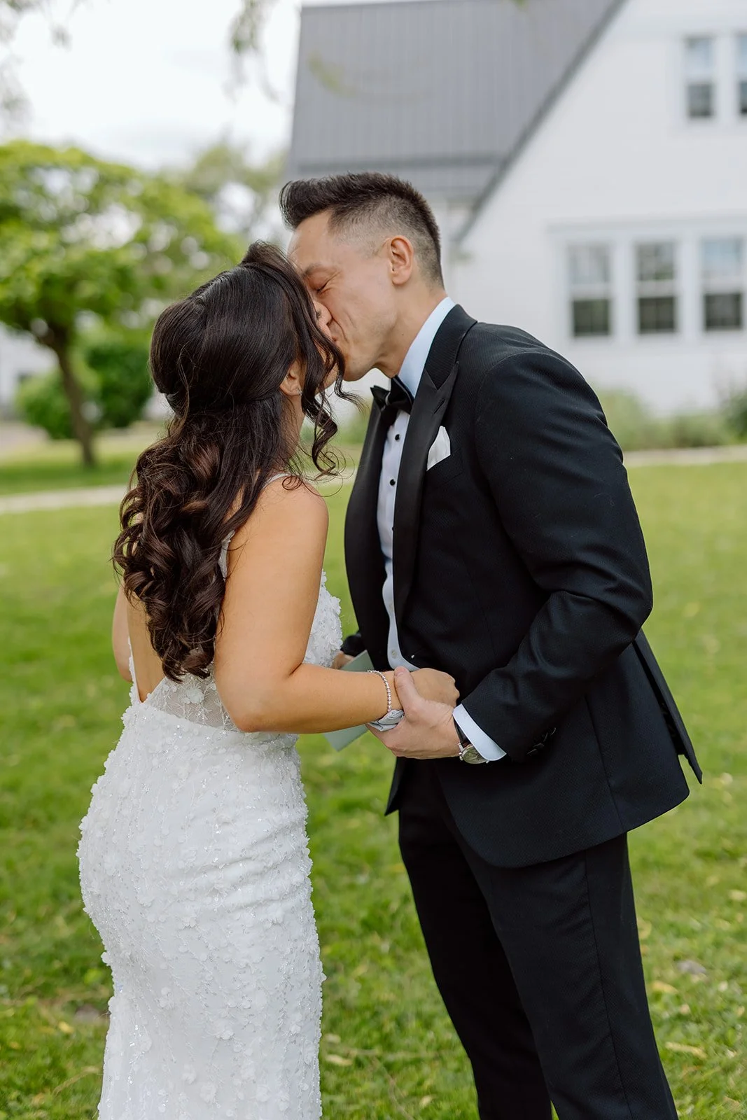  Bride and groom holding hands on the lawn in front of the white estate building at Willhowfarm House, in Niagara on the Lake. 