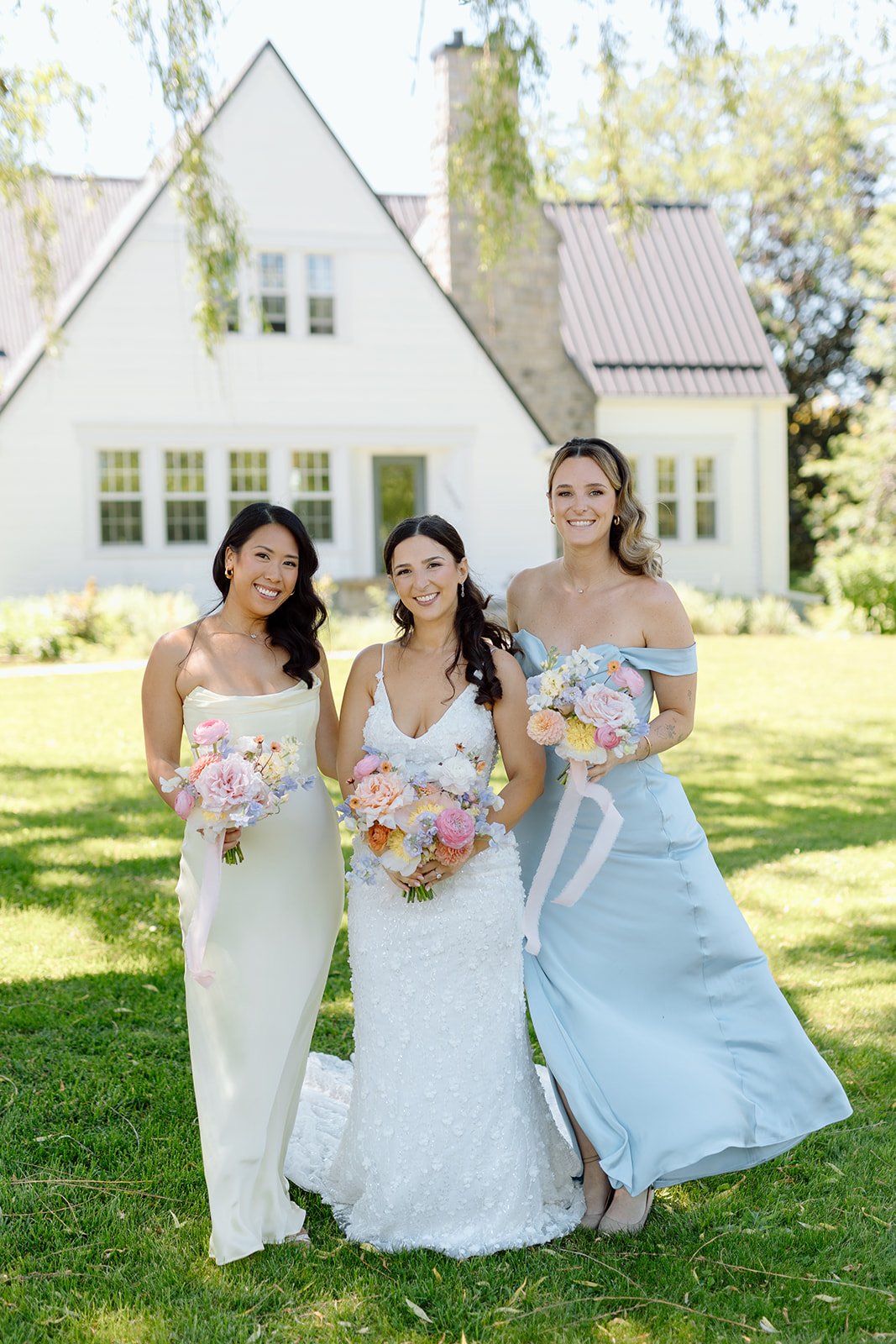  Bride and bridesmaids holding pastel bouquets at a vineyard wedding in Niagara. 