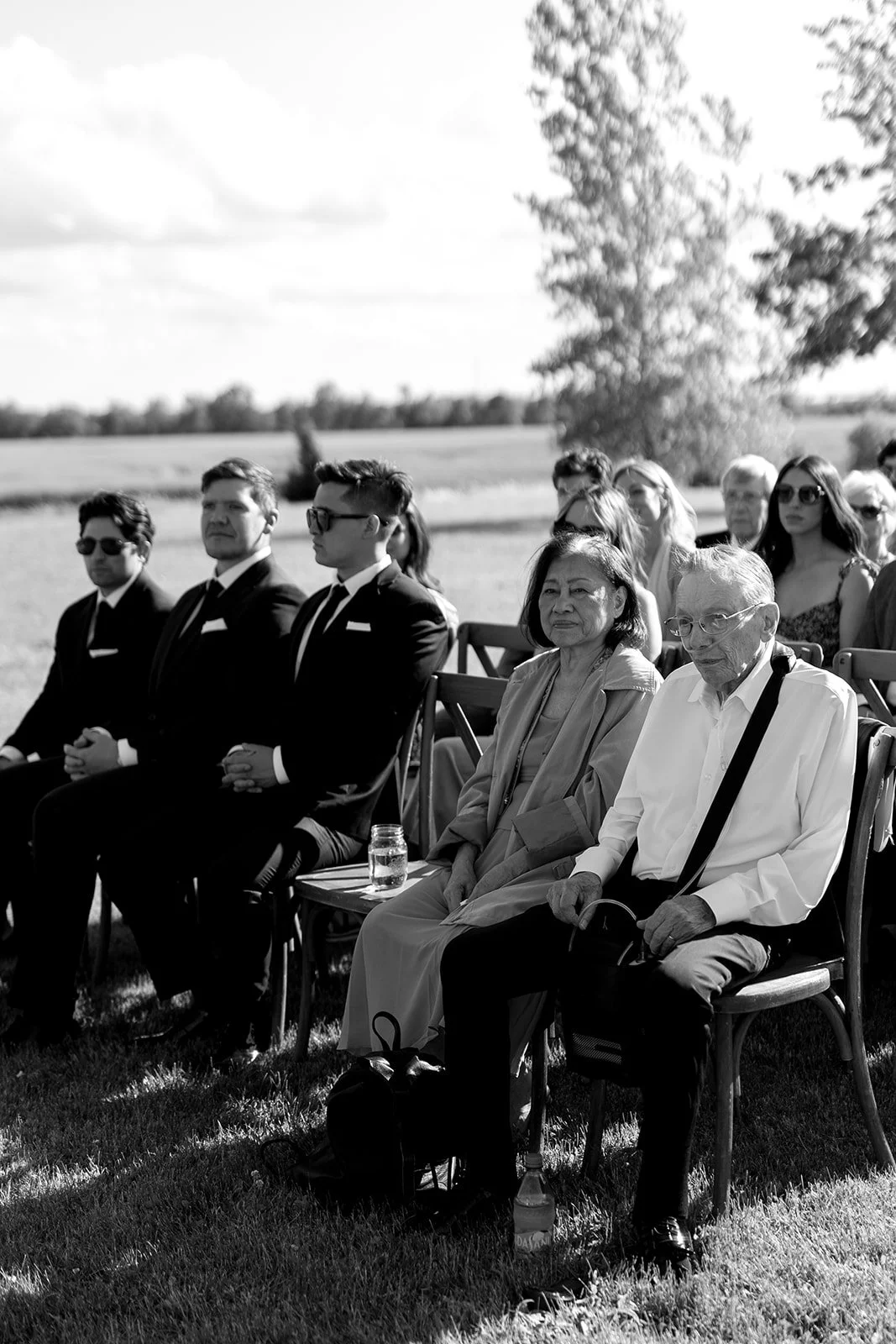  Vineyard wedding ceremony at The Hare Wine Co in Niagara-on-the-Lake, featuring a vibrant floral chuppah overlooking the rows of grapes. 