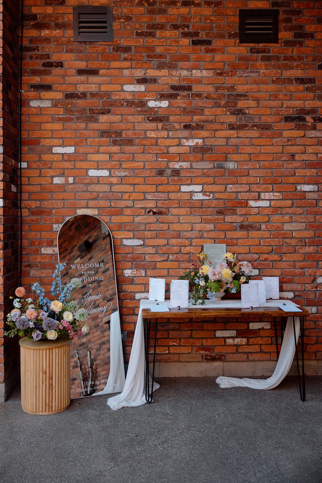 Seating chart display with custom florals by Threads &amp; Blooms, welcomes guests into the courtyard for dinner at The Hare Wine Co. 