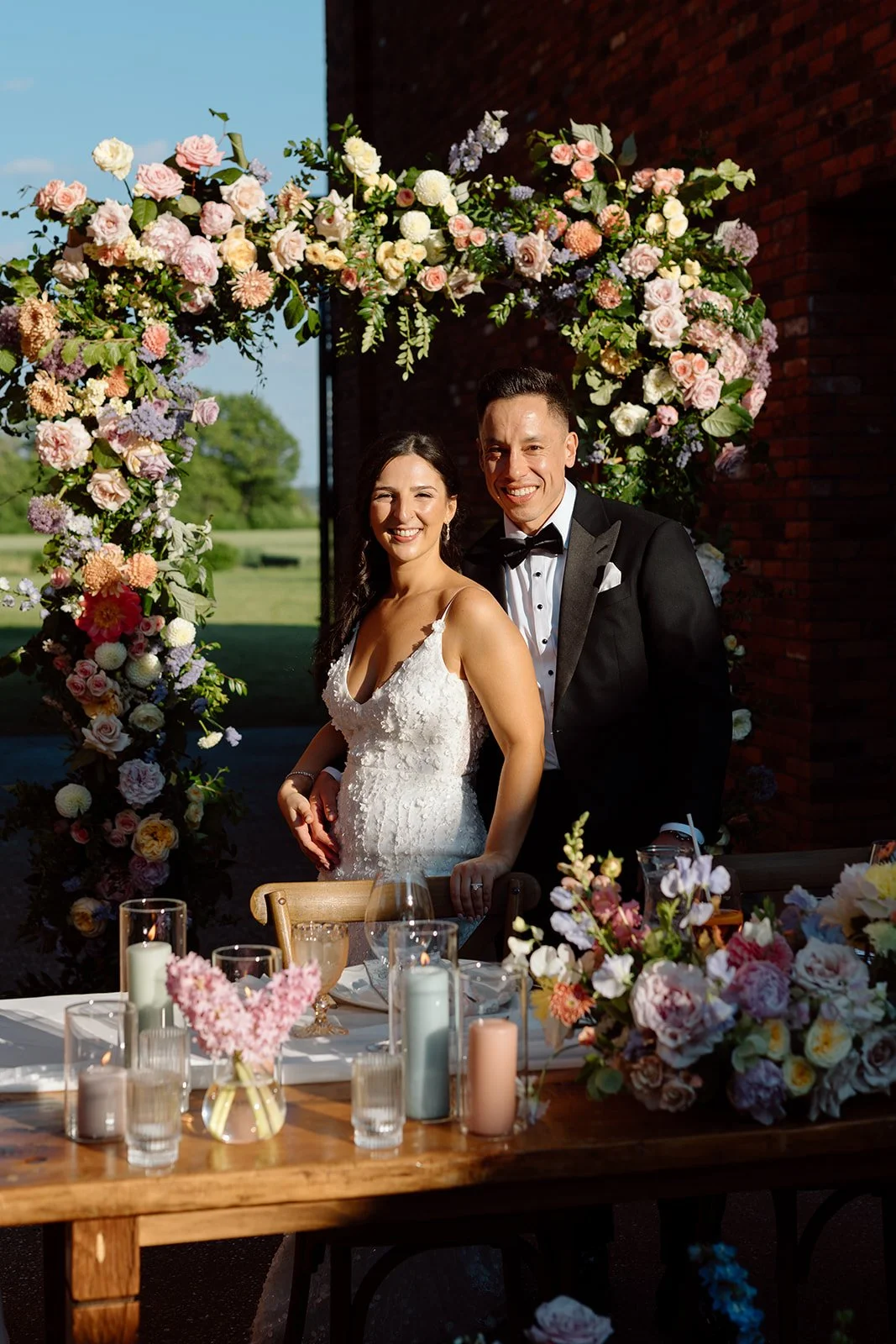  Lush, asymmetric floral wedding arch design with dahlias, roses, and garden flowers. 