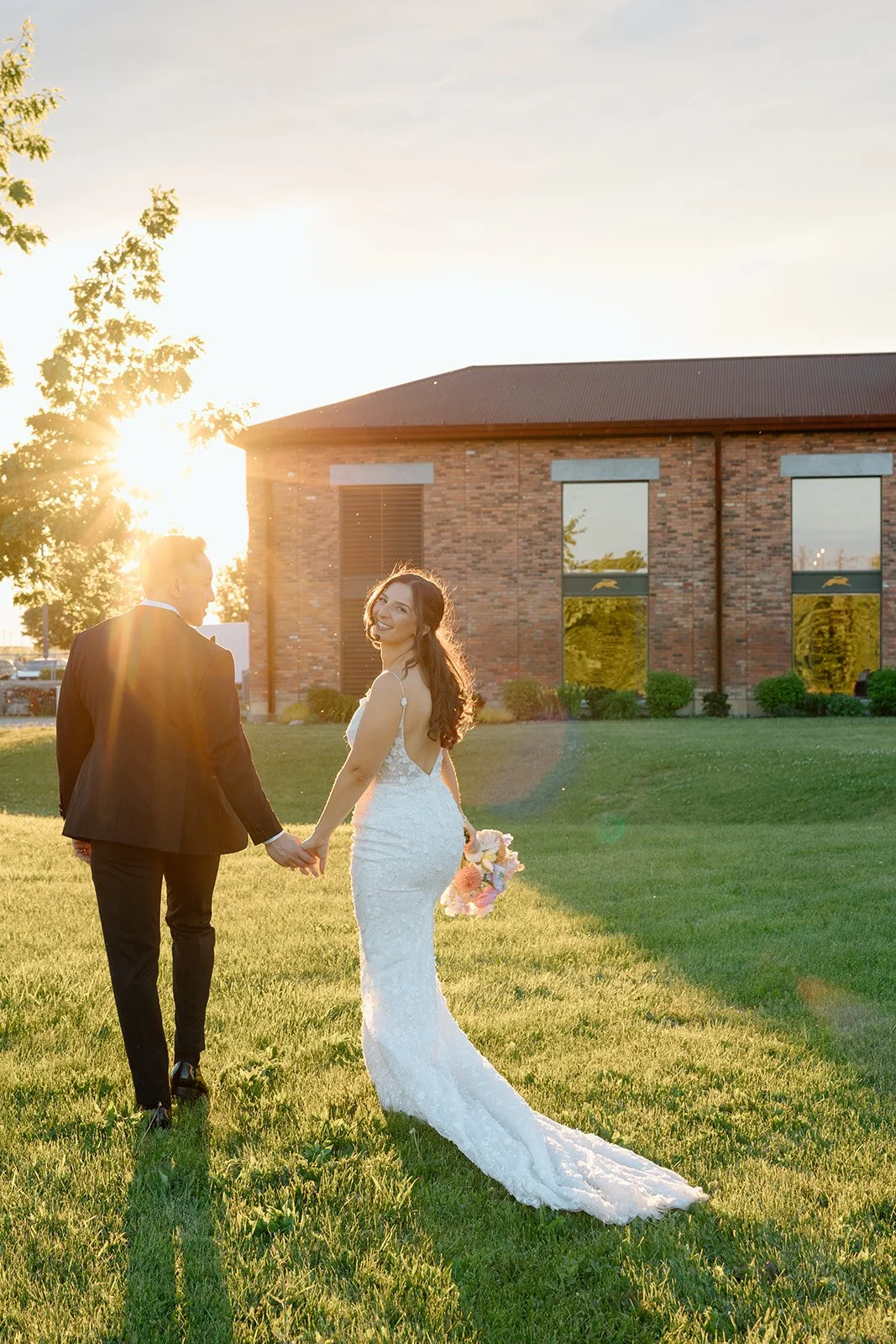  Newlyweds walking outside the estate building during a wedding at The Hare Wine Co. during sunset in Niagara on the Lake. 