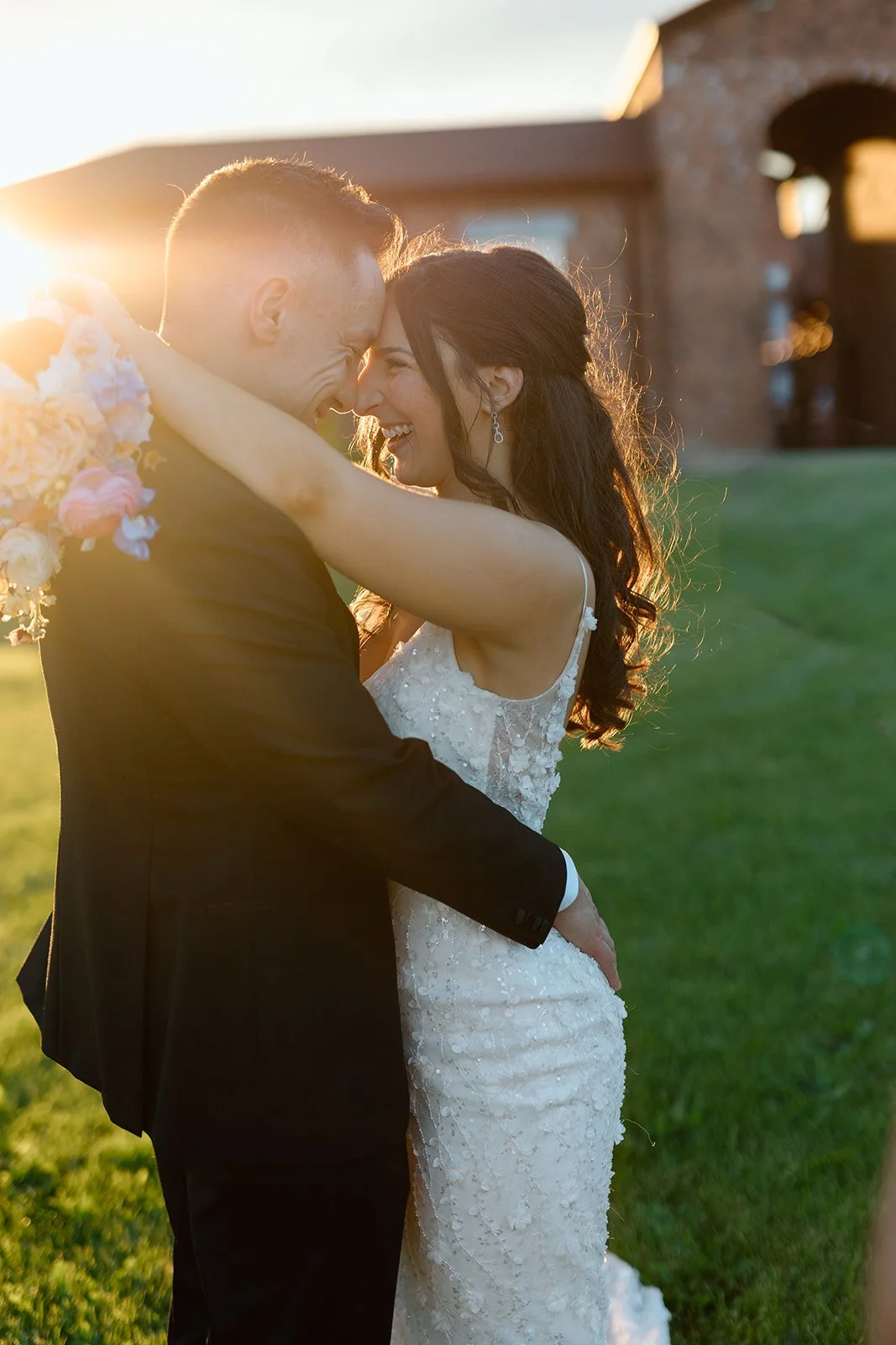  Romantic golden hour wedding portrait at a Niagara winery featuring a backlit bride and groom smiling during sunset. 