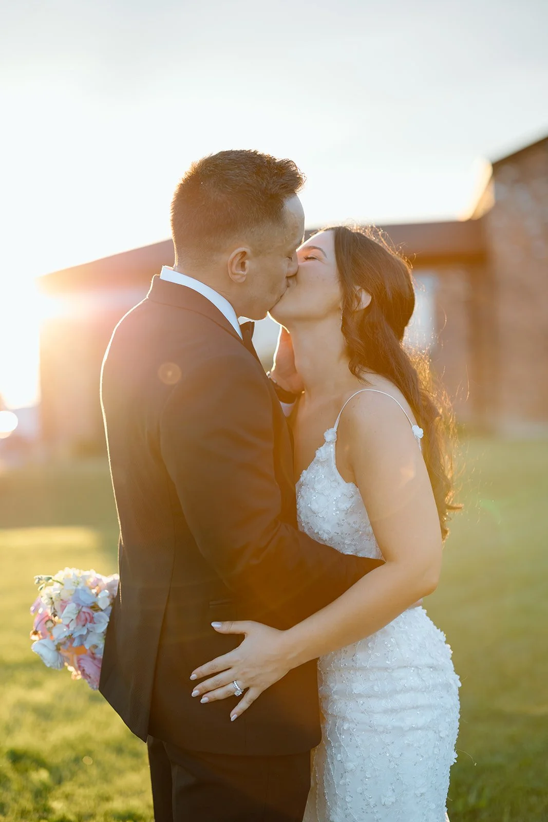  Newlyweds kissing in a golden field at sunset during their winery wedding reception, photographed by Paula Visco 