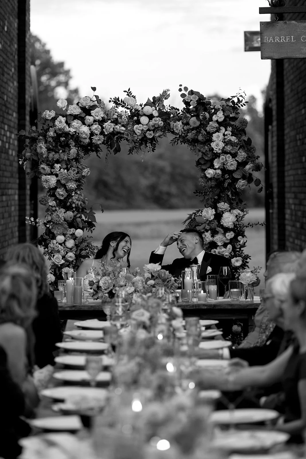  Bride and Groom share a laugh during toasts by their family and friends, underneath the golden hour sun in the Courtyard at The Hare Wine Co. 