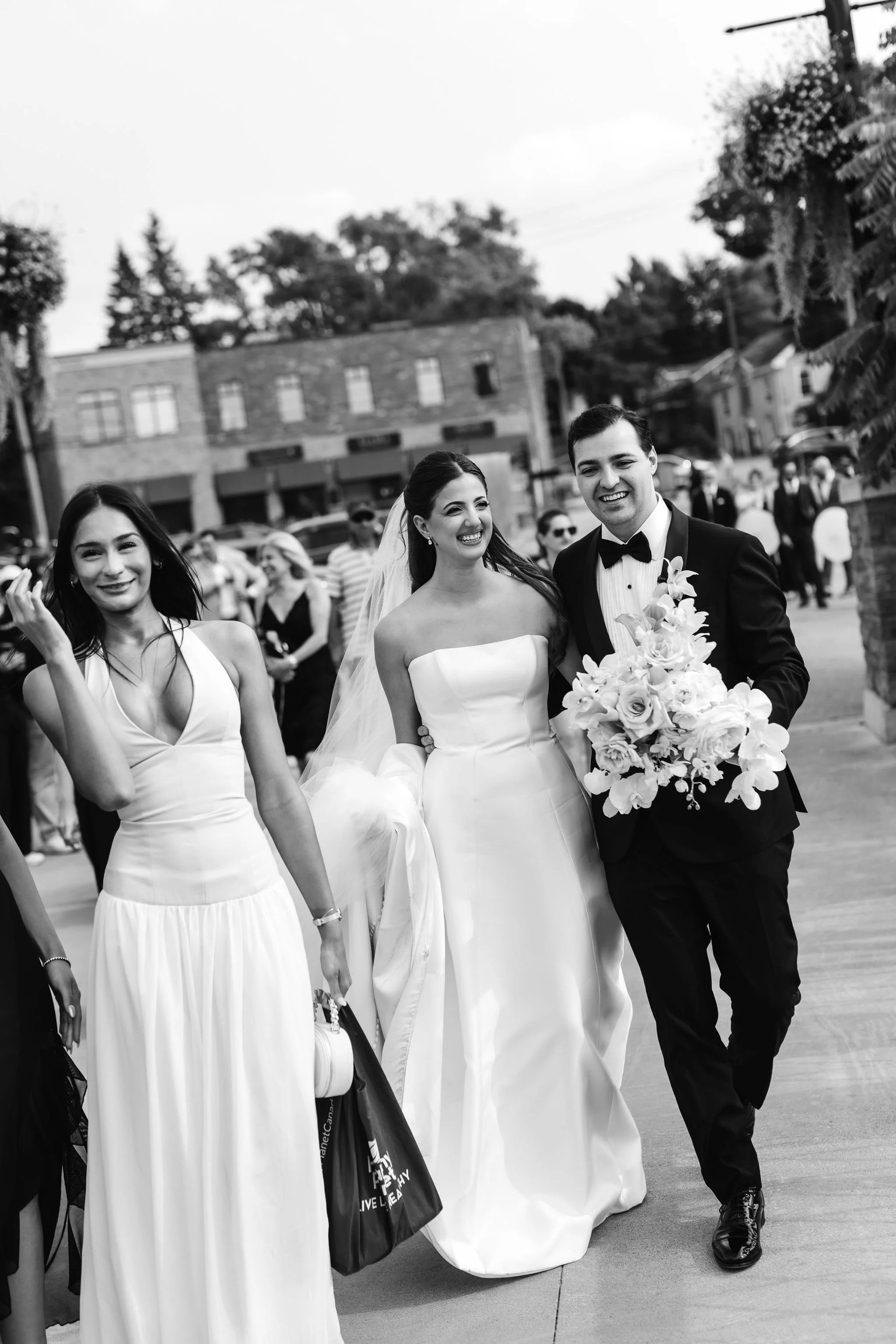 Bride and groom walk with their guests to their reception at Elora Mill