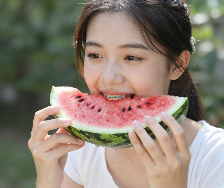 Teen girl with braces eating watermelon outdoors in summer