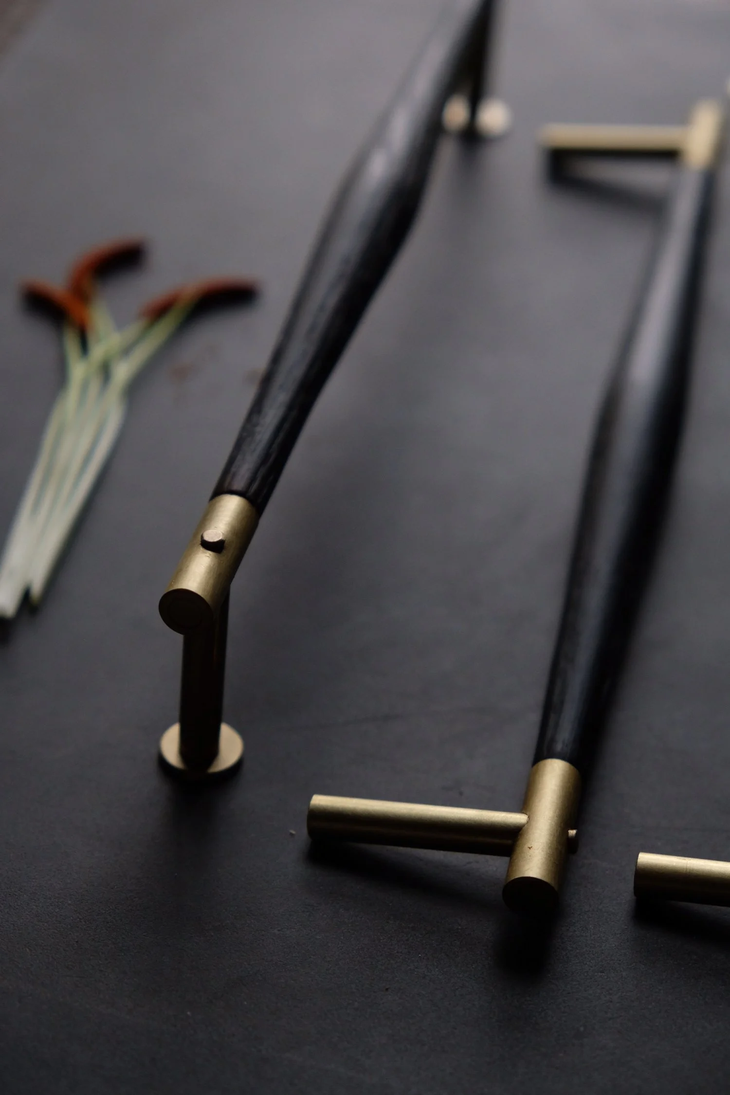Collection of billiard cues lying on a black surface with a set of colored toothpicks in the background.