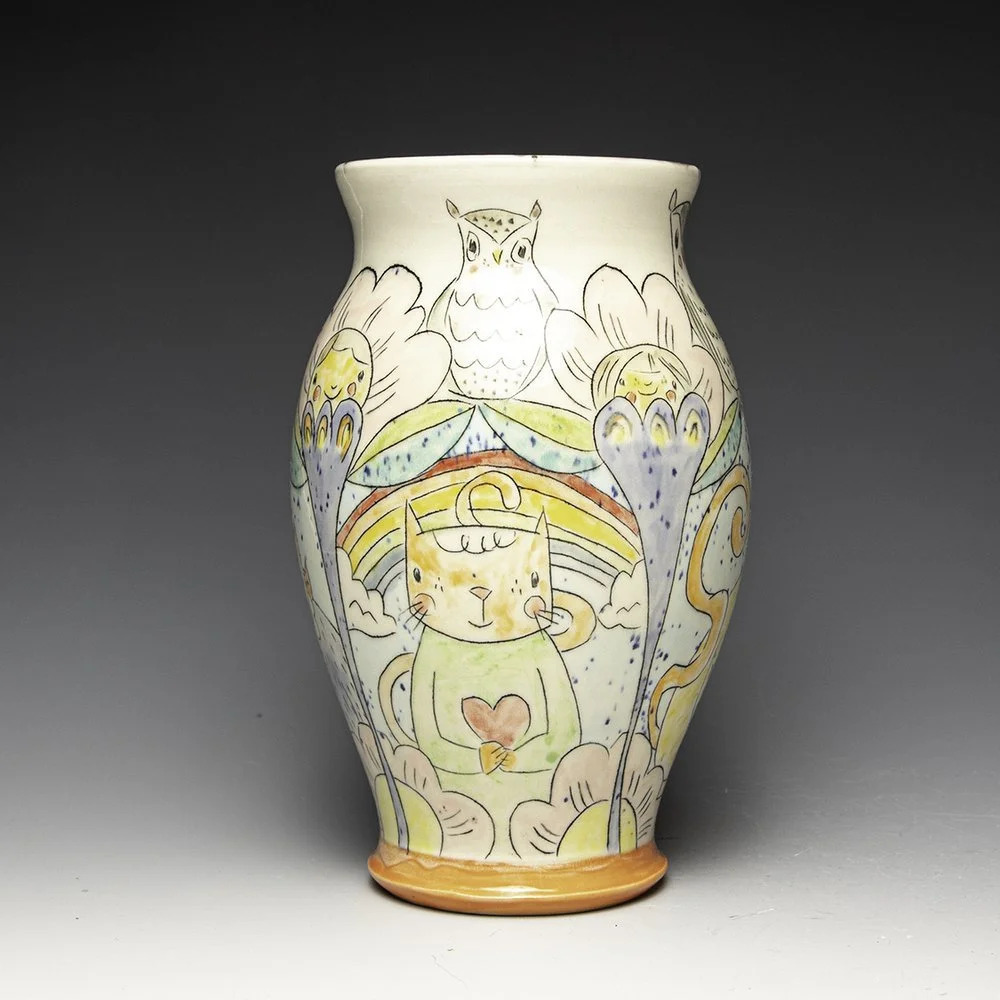 Colorful decorative vase featuring hand-drawn animals including an owl, a cat holding a heart, and other whimsical elements with vibrant colors.