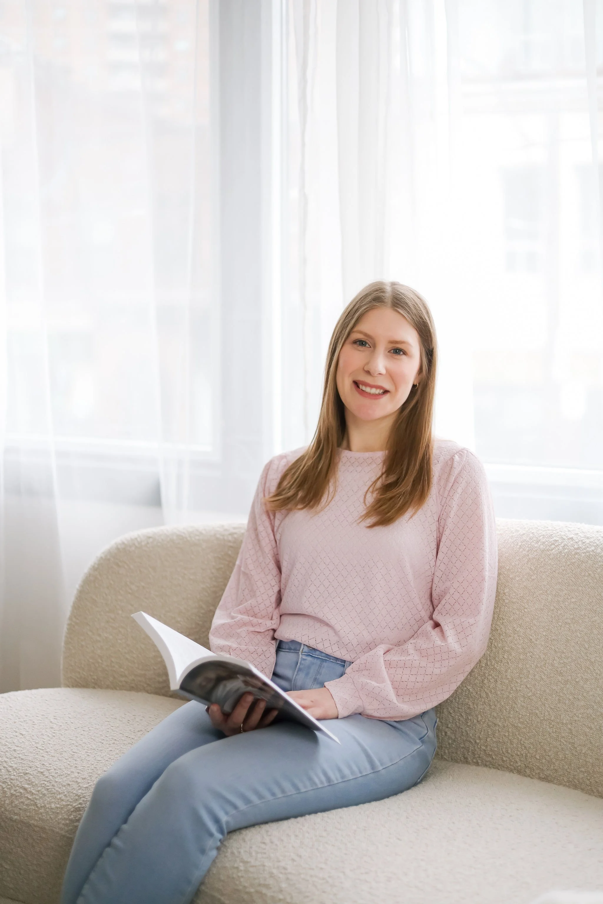 Registered Social Worker Kate Bailey holding a clinical resource, specializing in evidence-based trauma and perinatal therapy for women at Anchor Point Therapy.