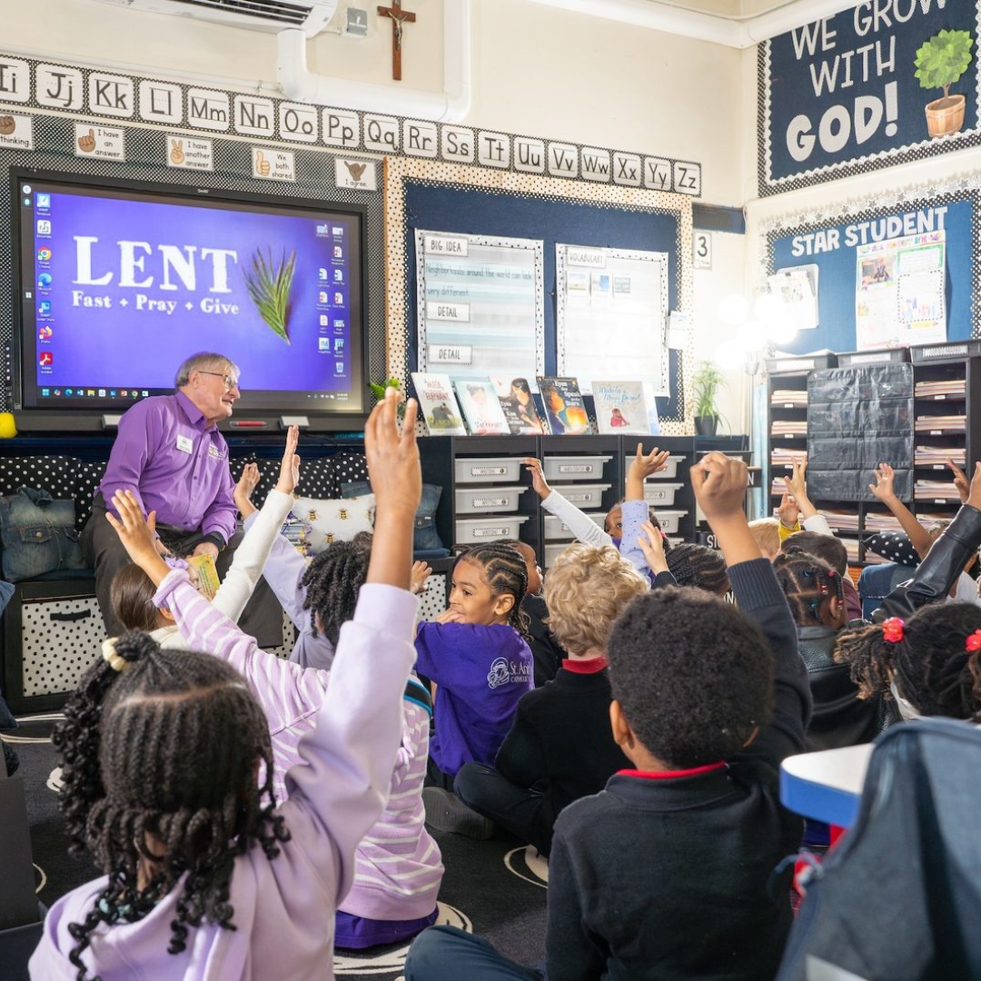 Dennis Dulniak talks with elementary students as children raise their hands during a Nana’s Books Foundation classroom visit.
