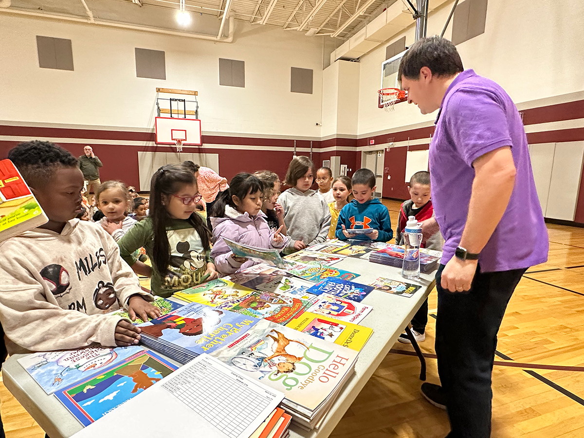 Mark distributing books to Pond Gap students