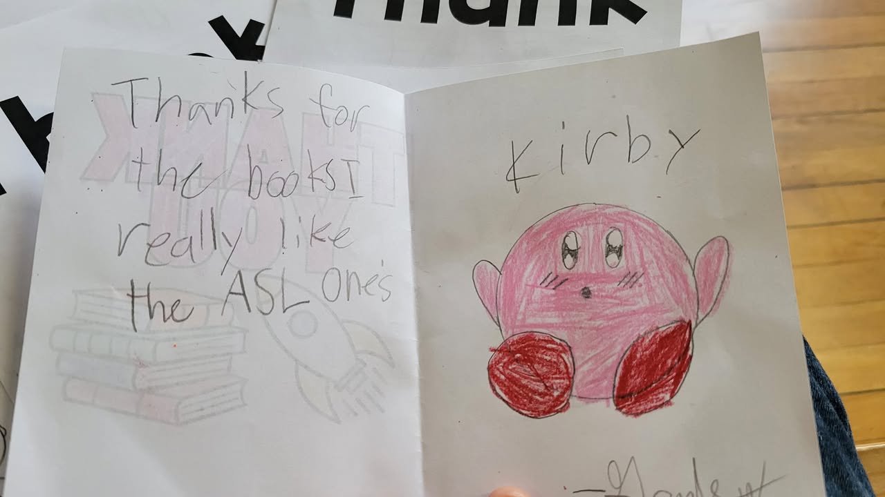 A handwritten thank-you note from a Mooreland Heights Elementary student with a drawing of Kirby and a message thanking Nana’s Books Foundation for the books.