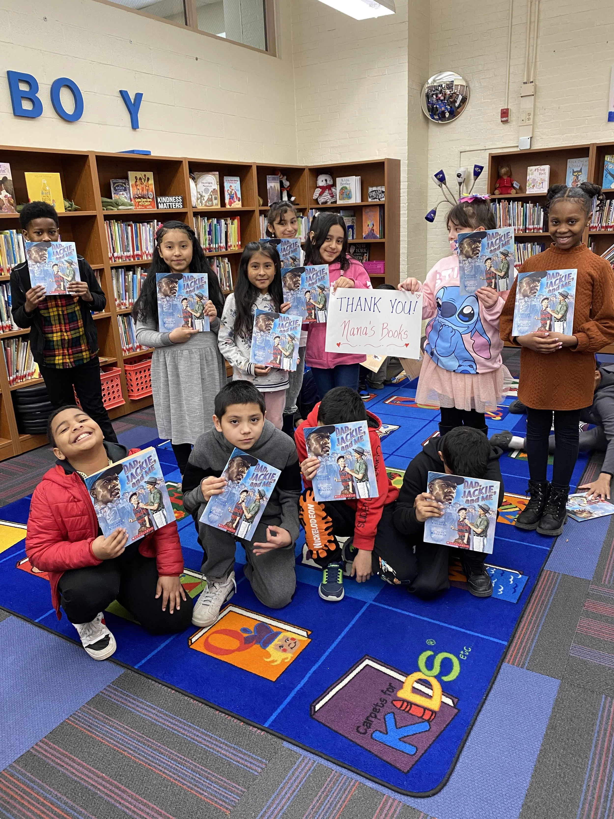 Owings Mills Elementary third-grade students hold donated books and a thank-you sign for Nana’s Books Foundation.