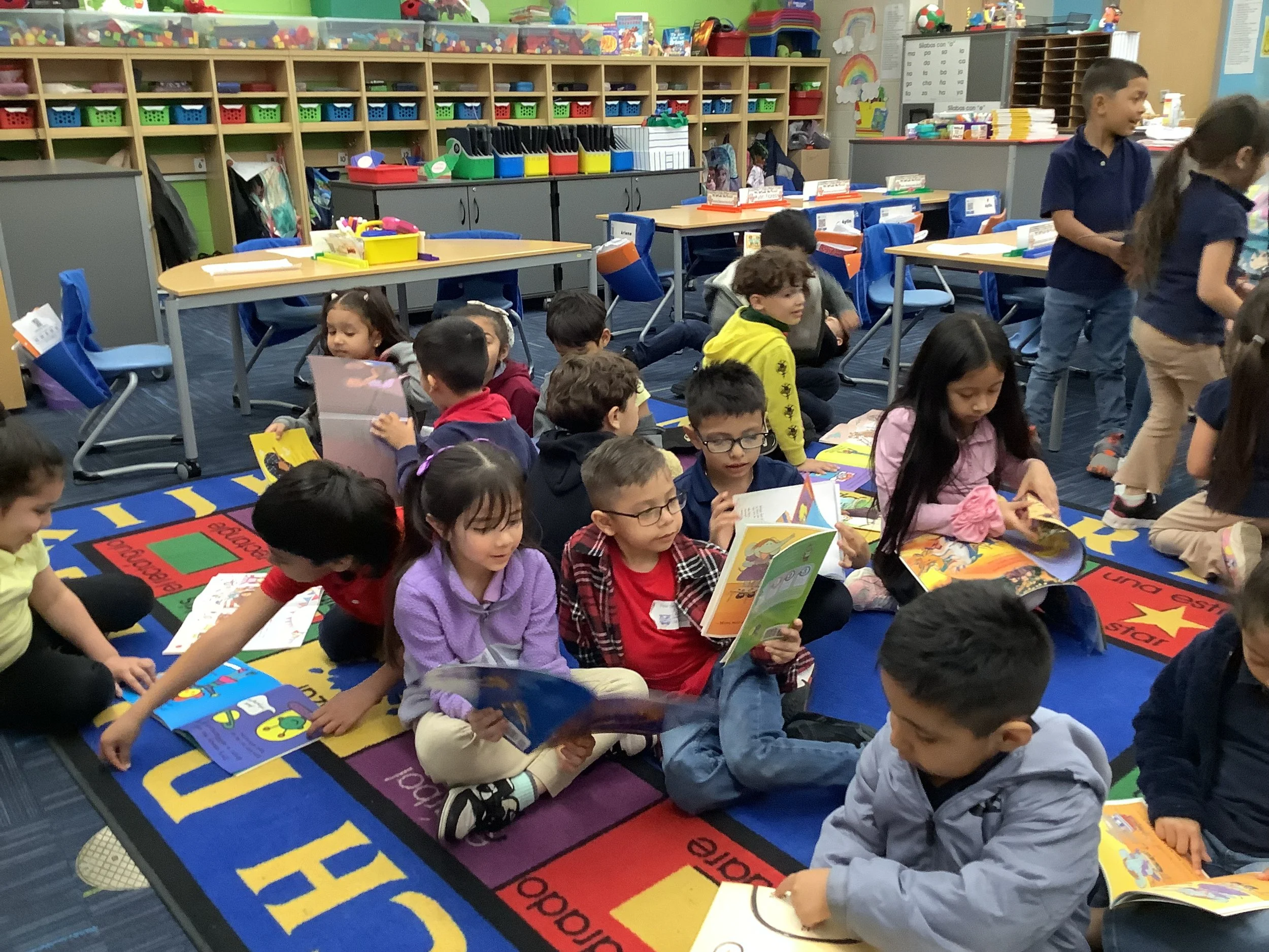 Elementary school students reading and exploring books together in a classroom.