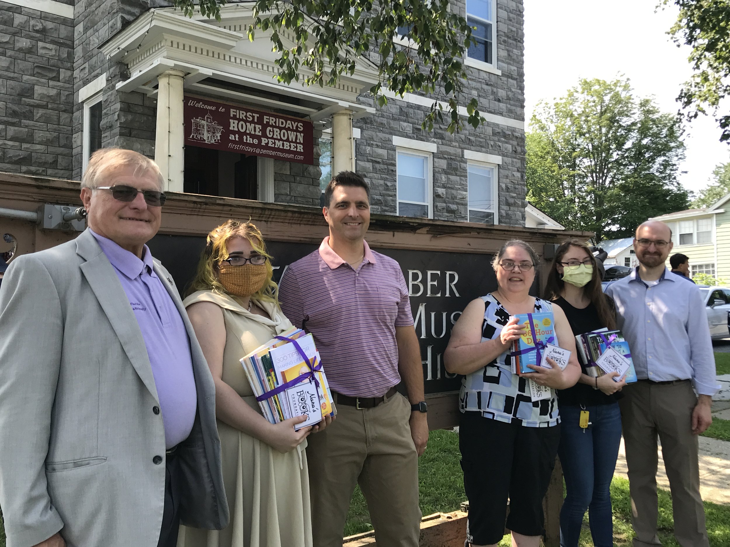 Nana’s Books Foundation representatives and Pember Library staff gather with donated books during an early book distribution.