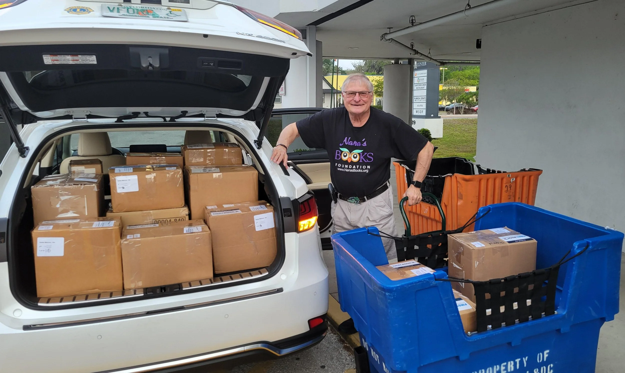 Dennis, founder of Nana’s Books Foundation, beside a vehicle filled with boxes of books ready for distribution.