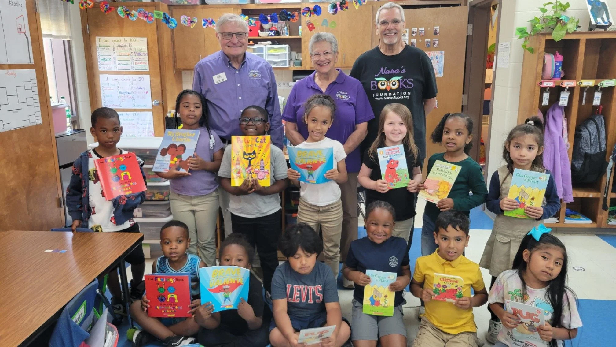 Nana’s Books Foundation volunteers with elementary students holding donated children’s books in their classroom.