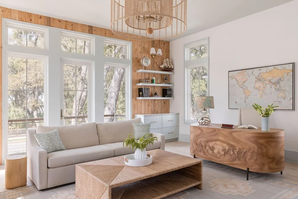 Bright living room with large windows, white sofa, wooden accents, and minimalist decor.