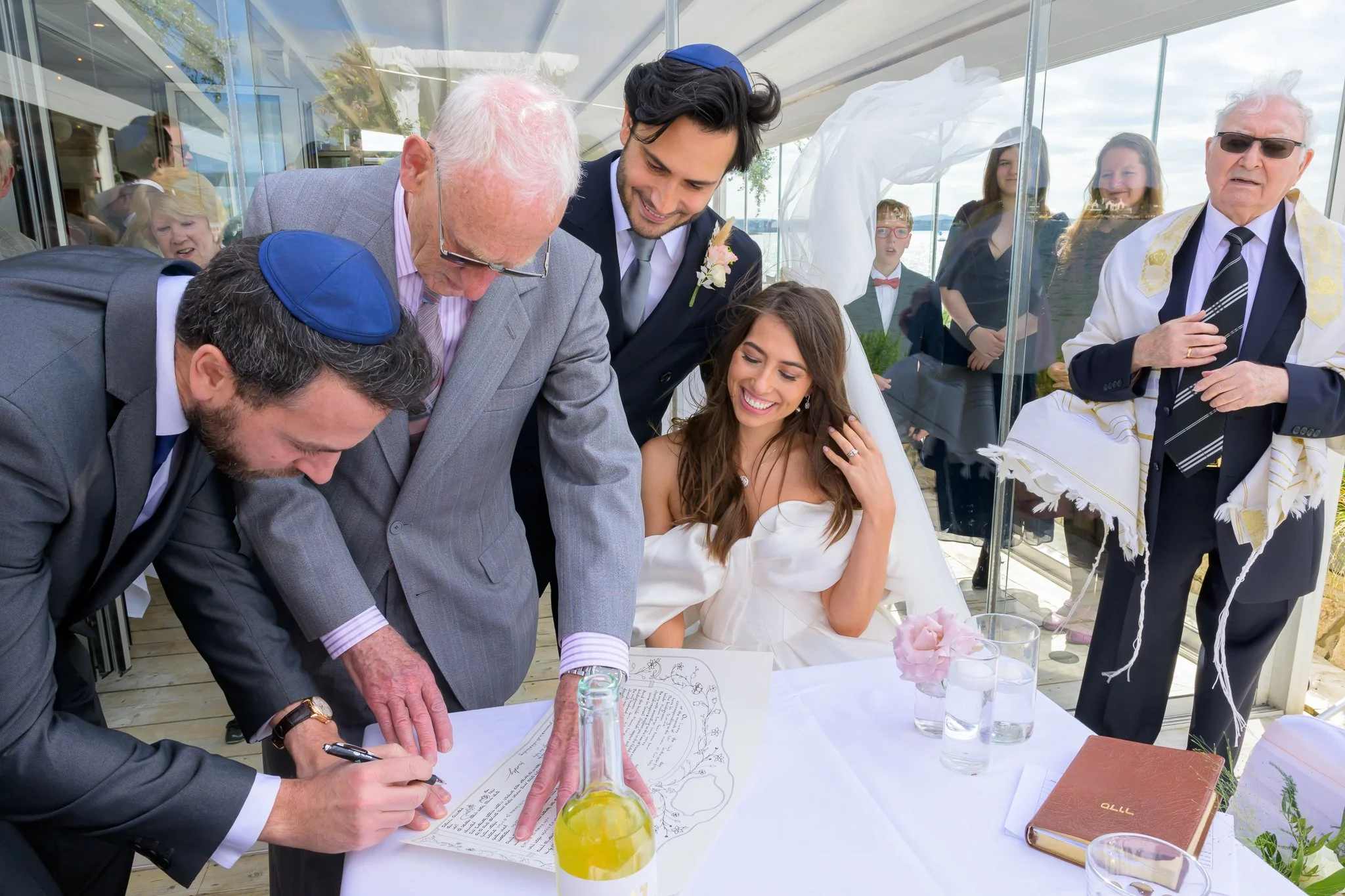 Bride and groom write their vows while their wedding guests stand around them, also helping them write their vows