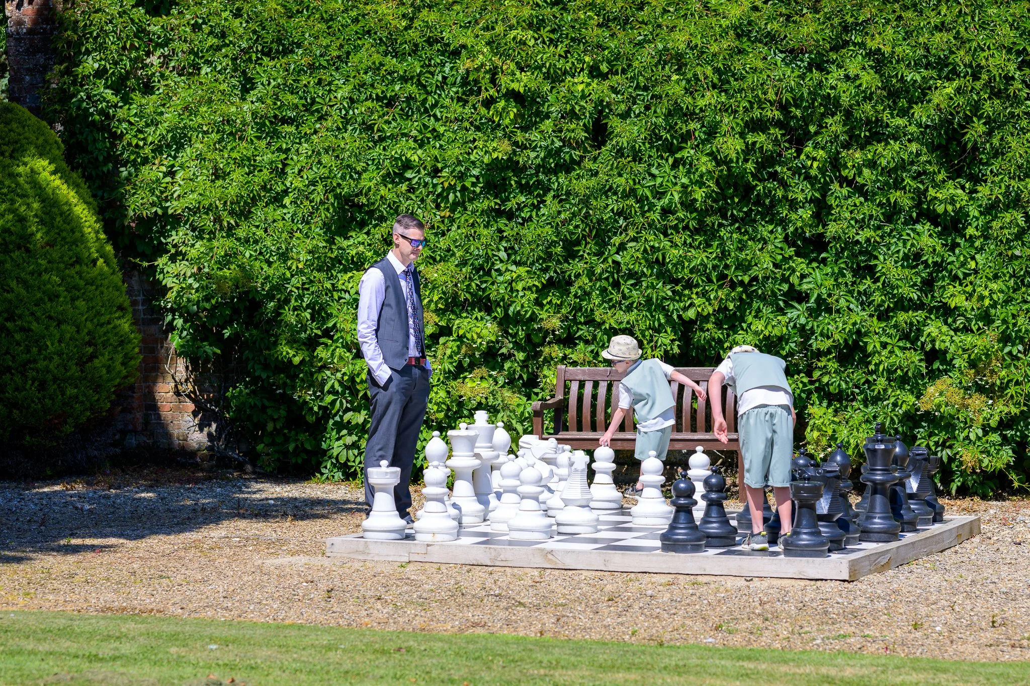 Wedding guests playing on a massive chess board with bushes in the background