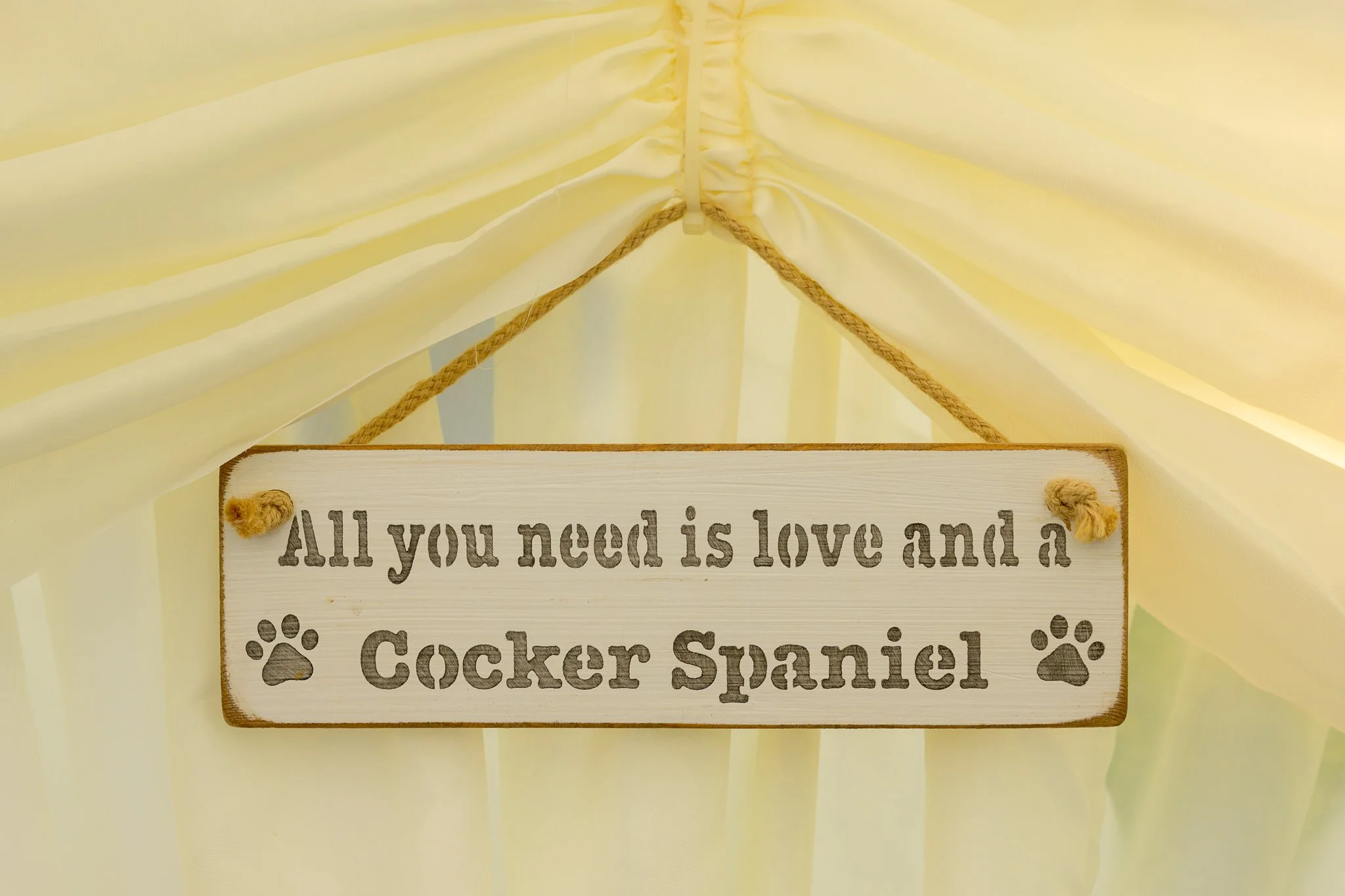 A hanging wooden board with writing on it saying 'All you need is love and a Cocker Spaniel'