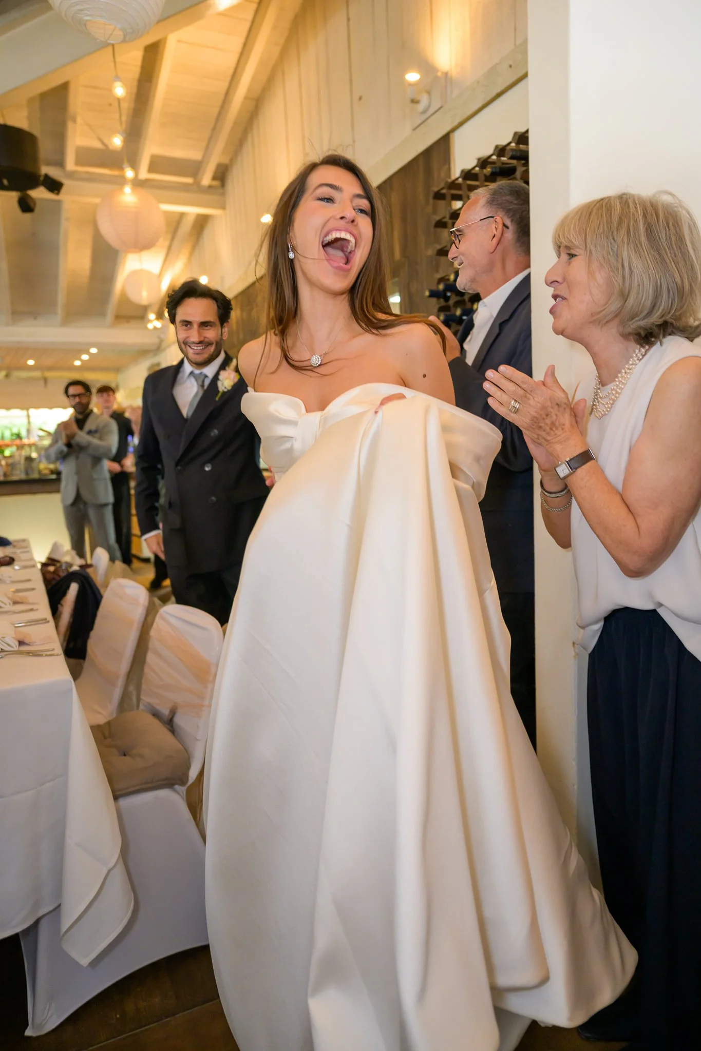 Bride laughing while standing inside her wedding venue, with the groom standing slightly behind her