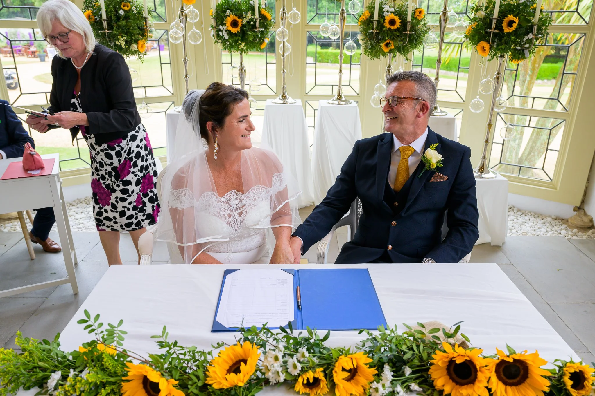 Bride and groom sat at a table ready to sign their wedding vows