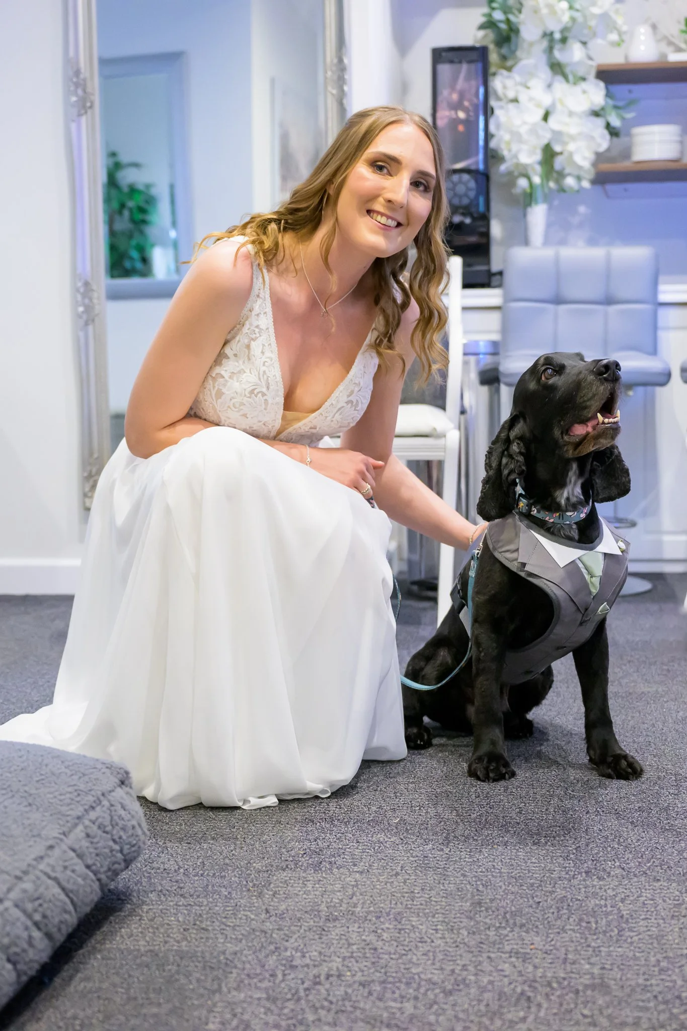 Bride smiling while sat next to and holding her black-coloured dog