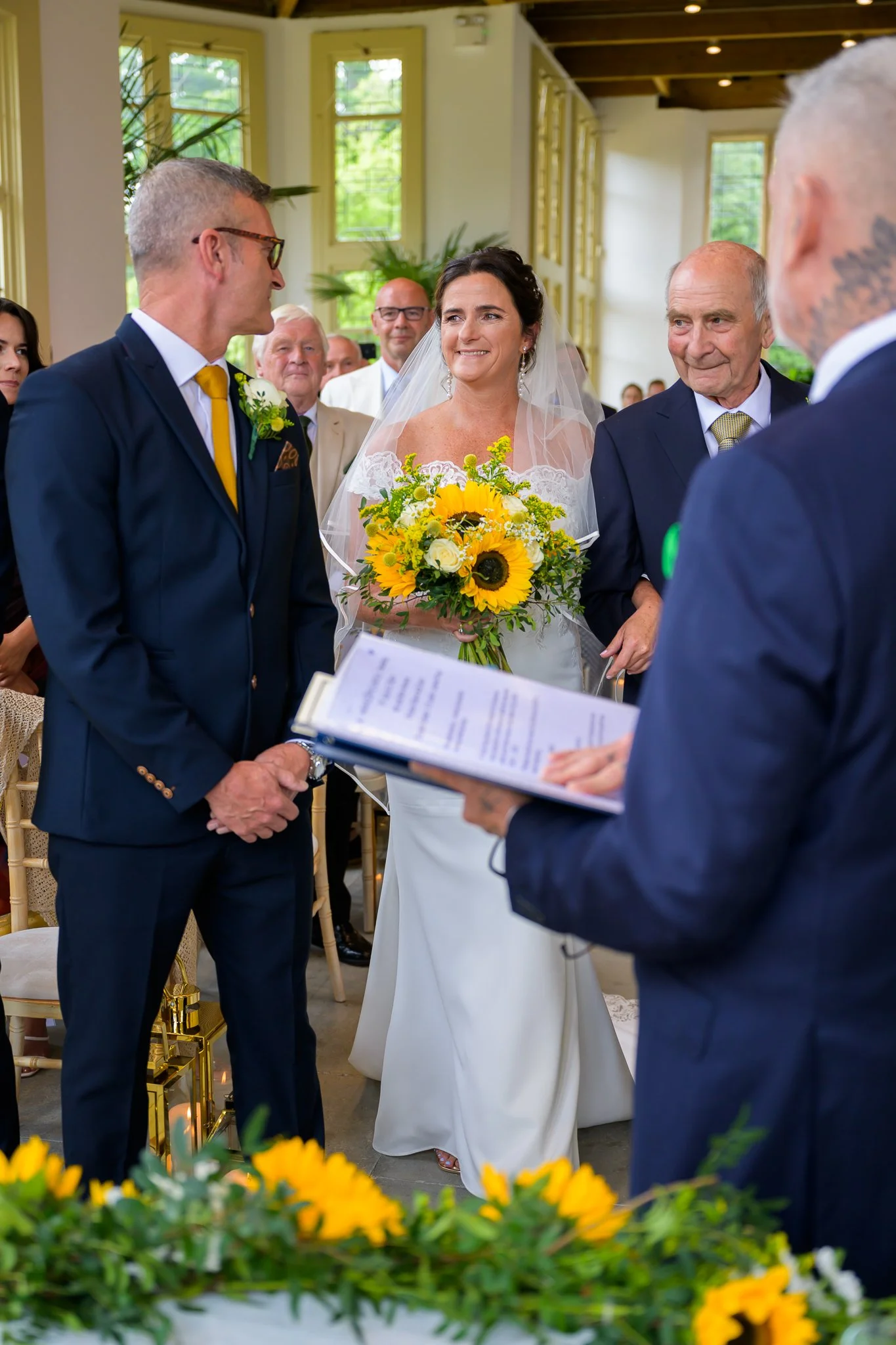 Bride and groom saying their vows with the marriage officiant holding the signage papers