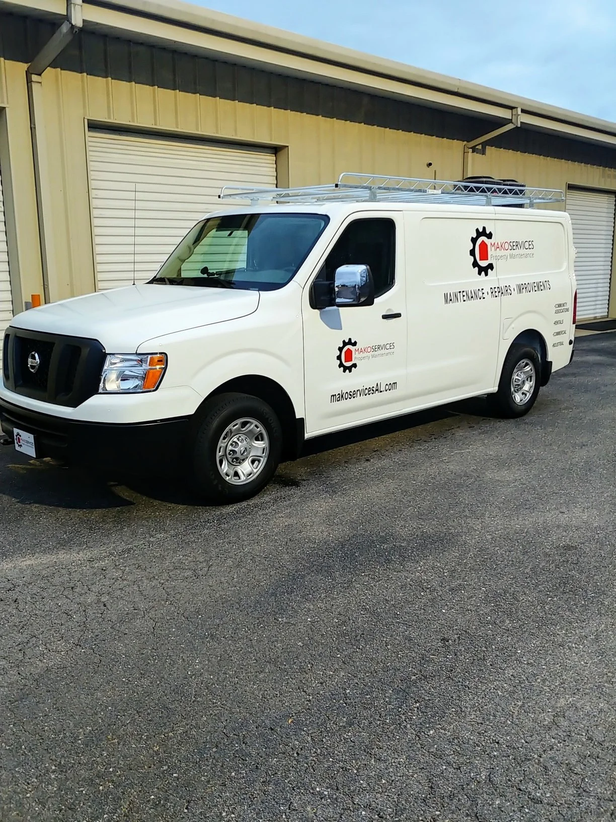 White service van with the logo and text for 'MAKO SERVICES Property Maintenance', parked on asphalt in front of a beige industrial building with closed roll-up doors.